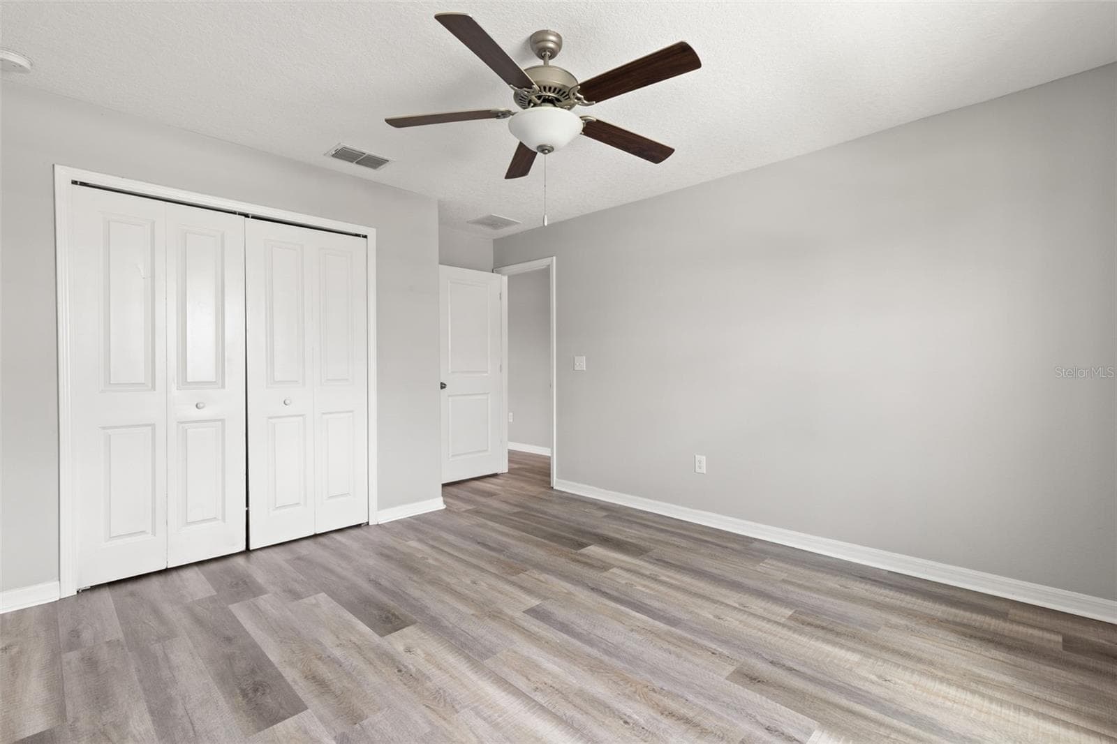 Bedroom 2 includes a wide double-door closet for ample storage, along with newly replaced laminate flooring, fresh neutral paint and a ceiling fan. - 5061 WHITE CHICORY DR, APOLLO BEACH