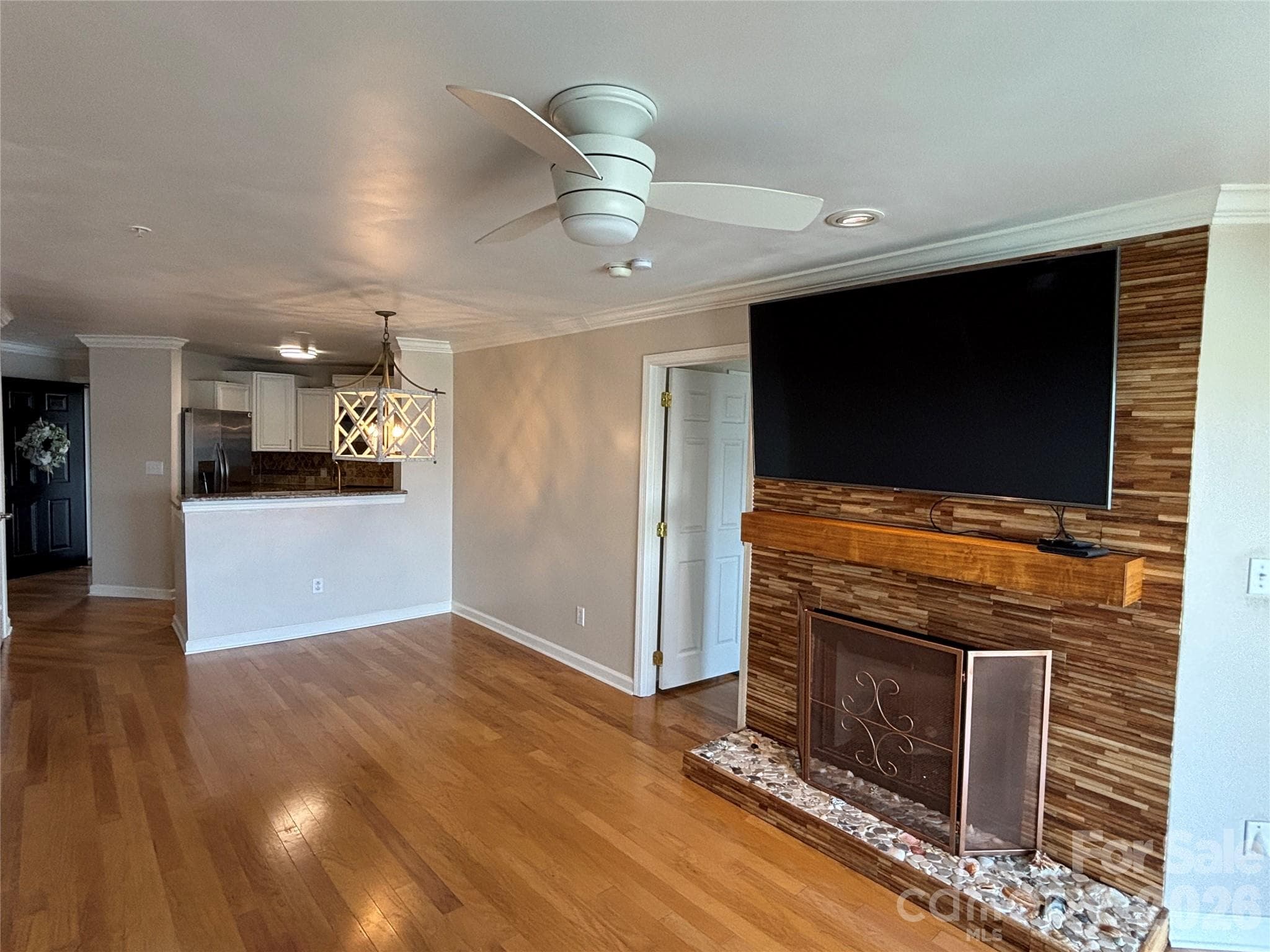Beautiful custom coastal teakwood gas log fireplace in your liivng room with LG smart TV to remain. Looking from the glass sliders to the Kitchen. Dining area next to the half wall. - 1332 Torrence Circle, Davidson
