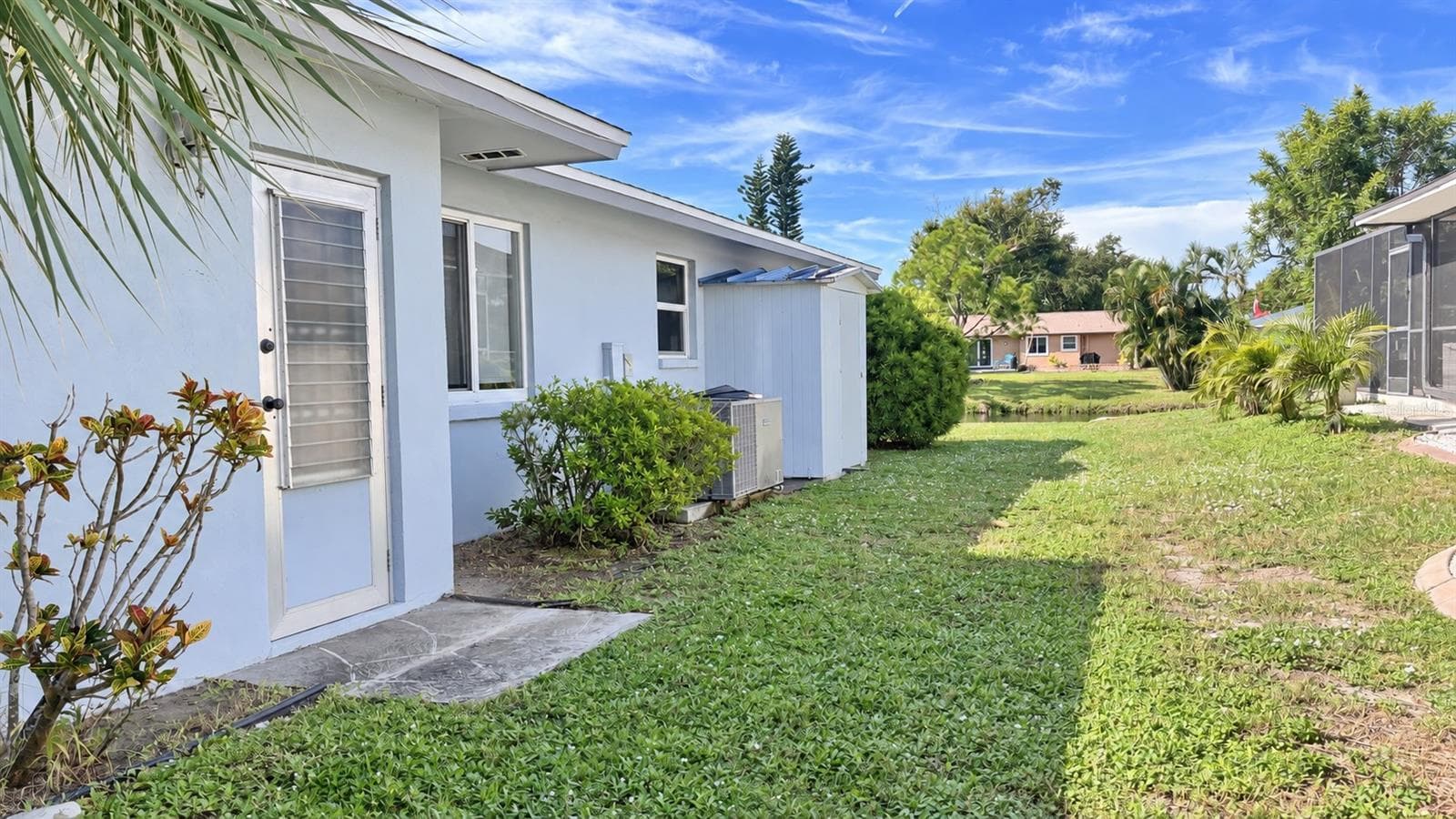 Side of home with doorway to garage, water side views, and storage shed. - 160 ANNAPOLIS LN, ROTONDA WEST