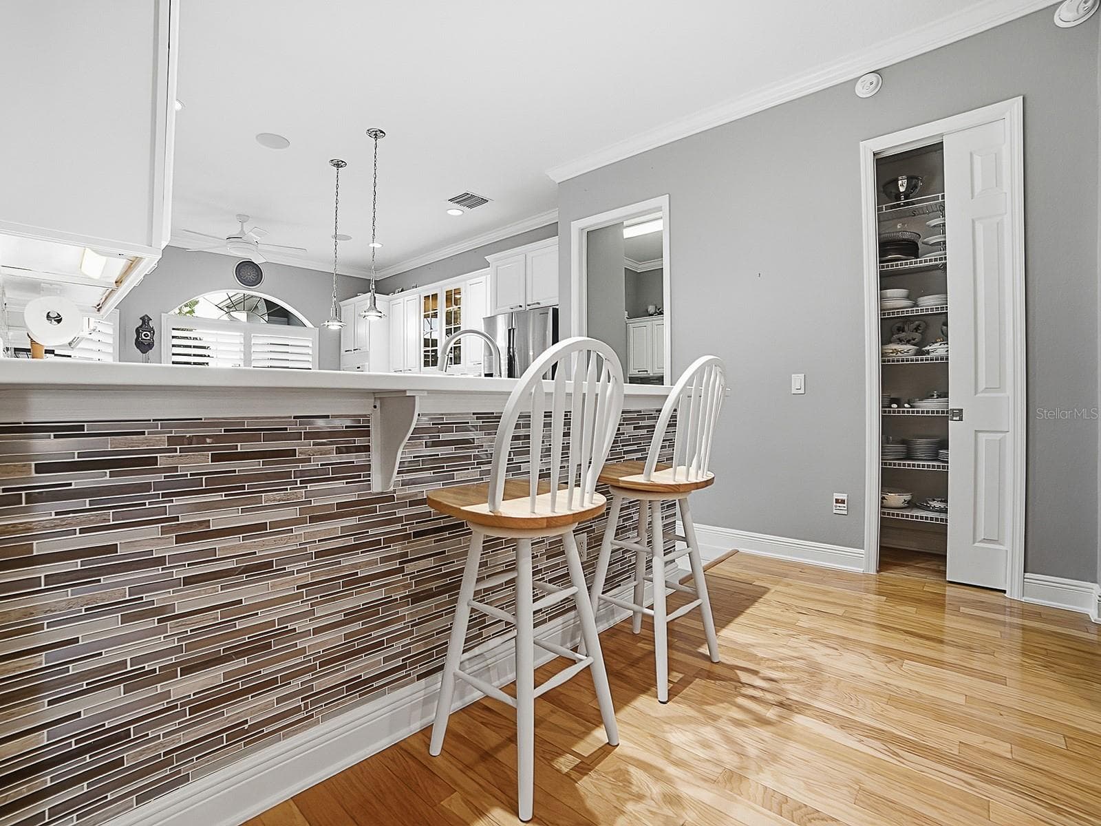 THE FRONT OF THE BREAKFAST BAR IS FINISHED OFF NICELY WITH THE SAME TILE AS THE BACKSPLASH. A CUSTOM CLOSET PANTRY WAS ALSO ADDED. THE DOOR TO THE LEFT OF THE PANTRY LEADS TO THE LAUNDRY ROOM. - 1897 HARTFORD PATH, THE VILLAGES
