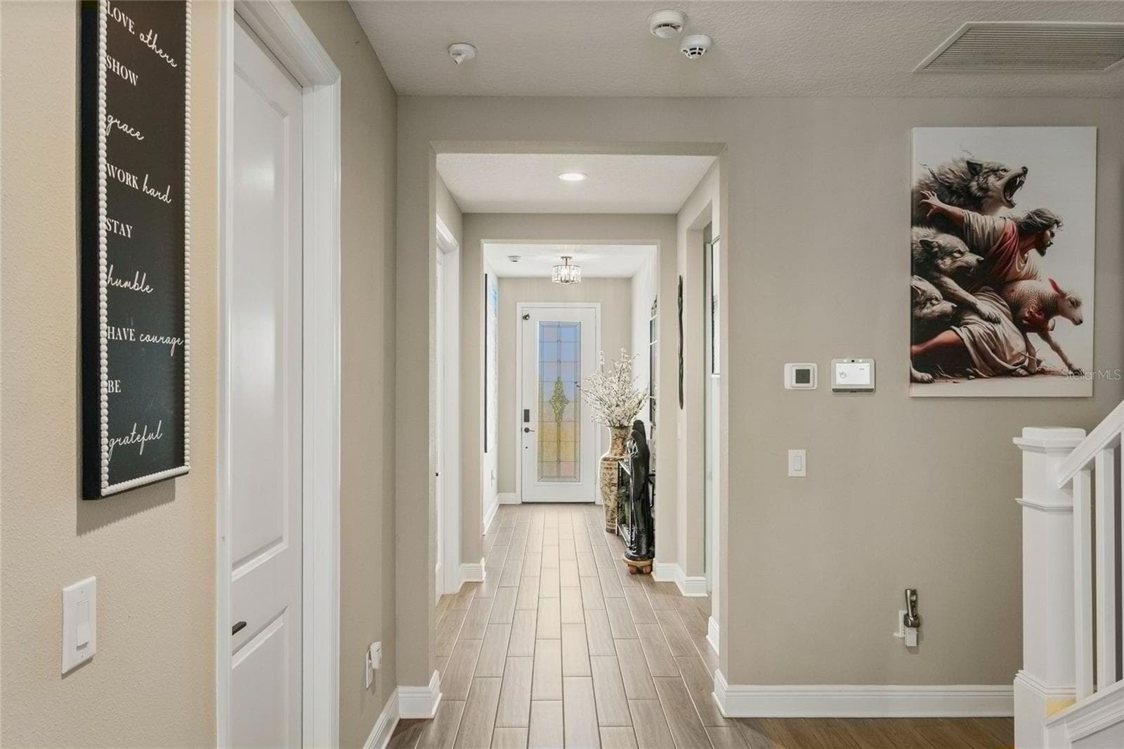 Elegant hallway with wood-look tile flooring, decorative glass entry door, modern chandelier, creating a refined, welcoming entry - 10625 FALLING LEAF CT, PARRISH