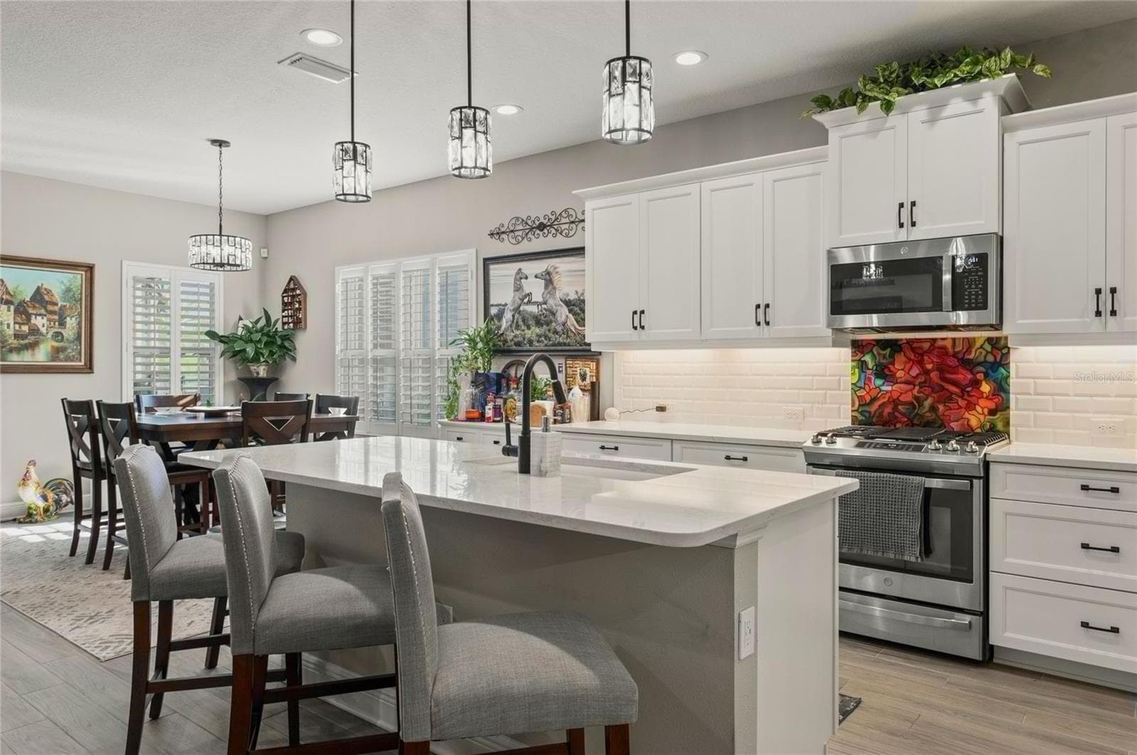 Modern kitchen with white cabinetry, quartz island, stainless-steel appliances, and pendant lighting that enhances the bright, open layout. - 10625 FALLING LEAF CT, PARRISH