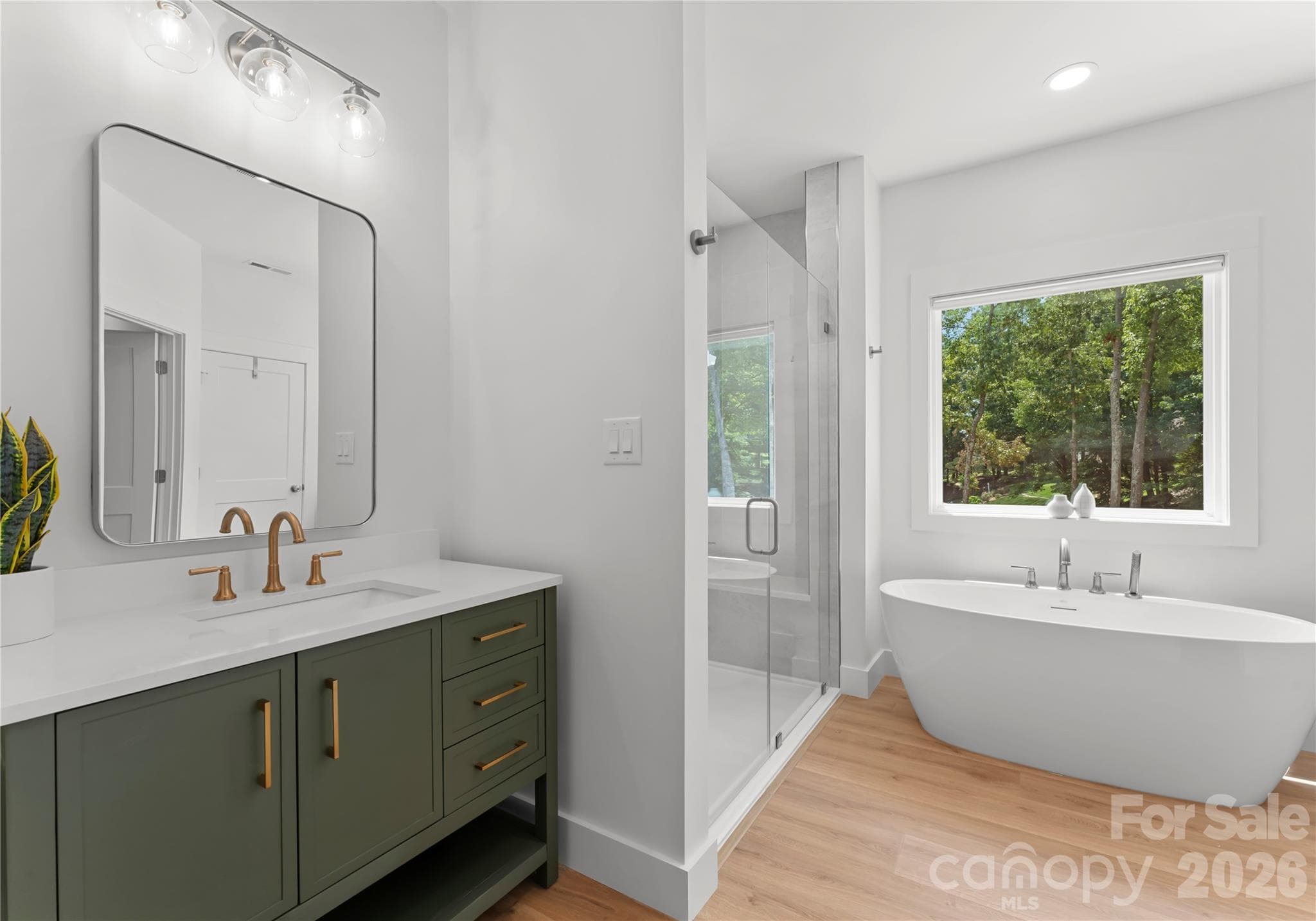 A sage-toned vanity and brass accents bring a refined touch to this bathroom, which connects directly to the adjoining bedroom. - 143 Hideaway Lane, Mooresville