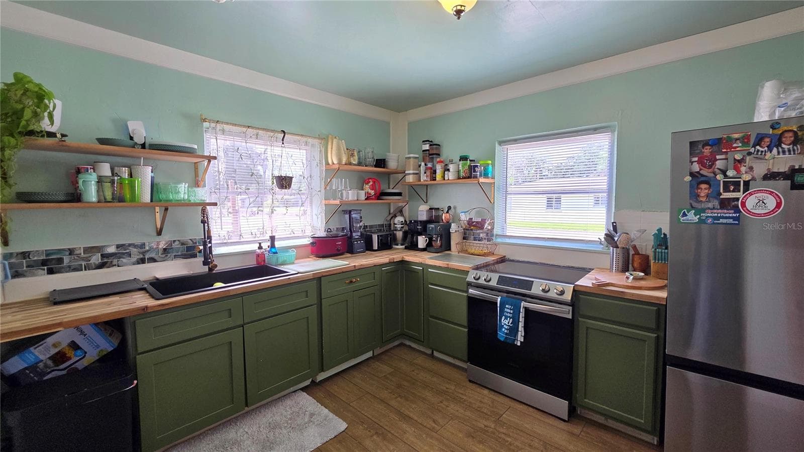 Kitchen with Butcher Block Countertops, Stainless appliances, Undermount Sink, Decorative Shelving, 2 Windows, and Laminate Flooring - 1702 26TH ST W, BRADENTON