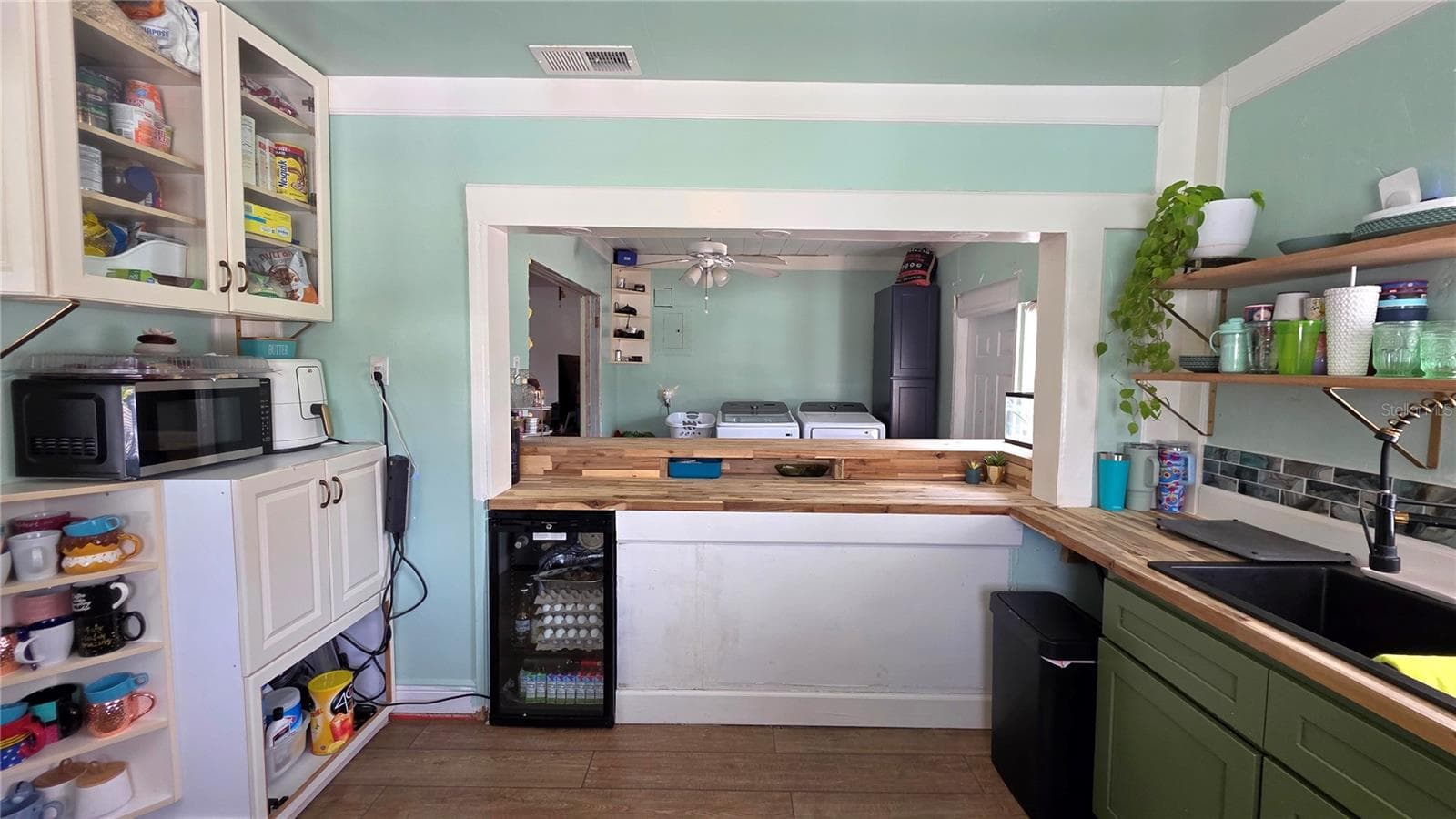 Kitchen Pass Through area to Breakfast Bar Seating, with Butcher Block Countertops, Stainless appliances, Decorative Shelving, 2 Windows, and Laminate Flooring - 1702 26TH ST W, BRADENTON