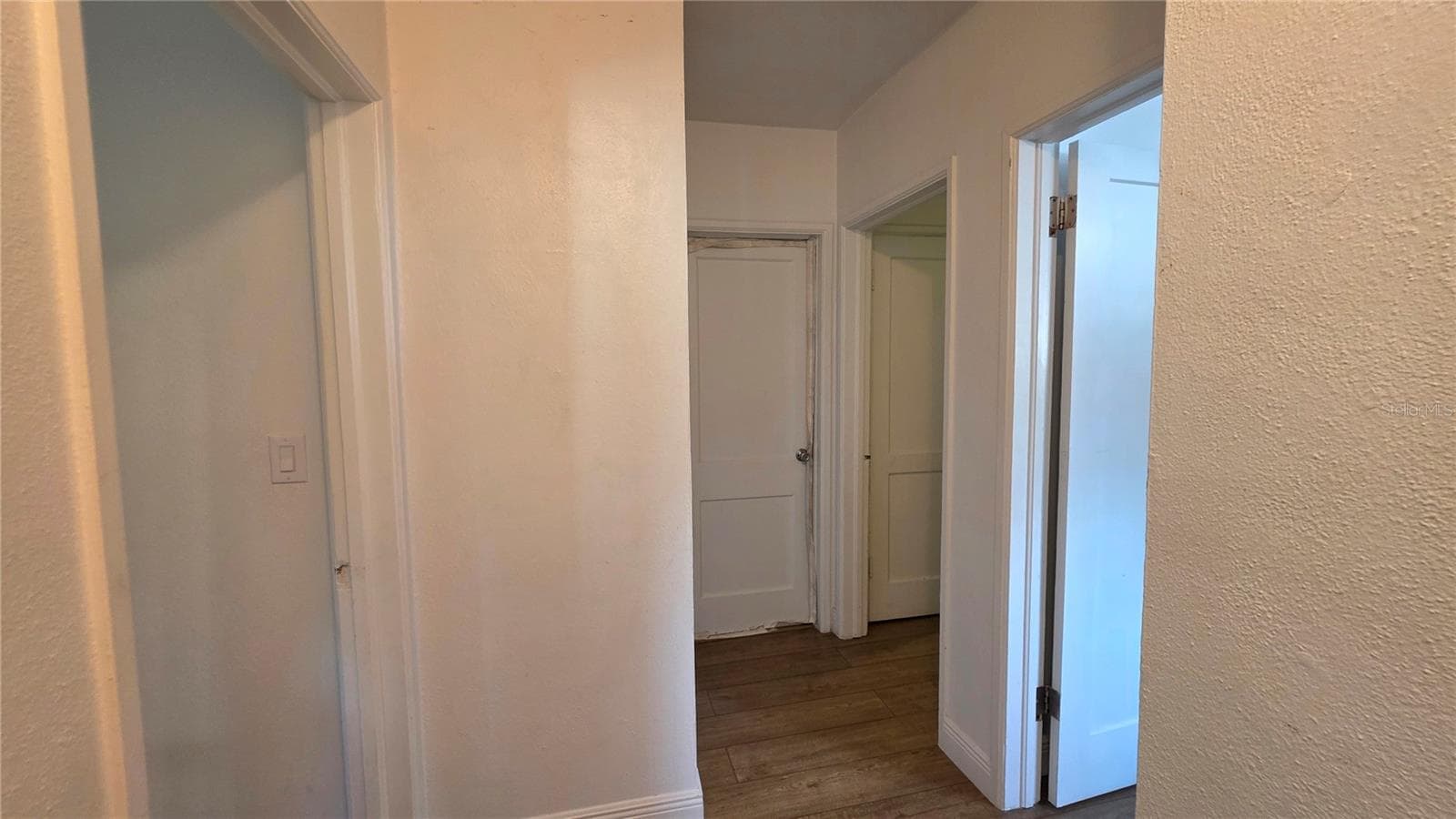 Hallway and Doors to Primary, 2 Bedrooms, and Full Bathroom (non-functional) - 1702 26TH ST W, BRADENTON