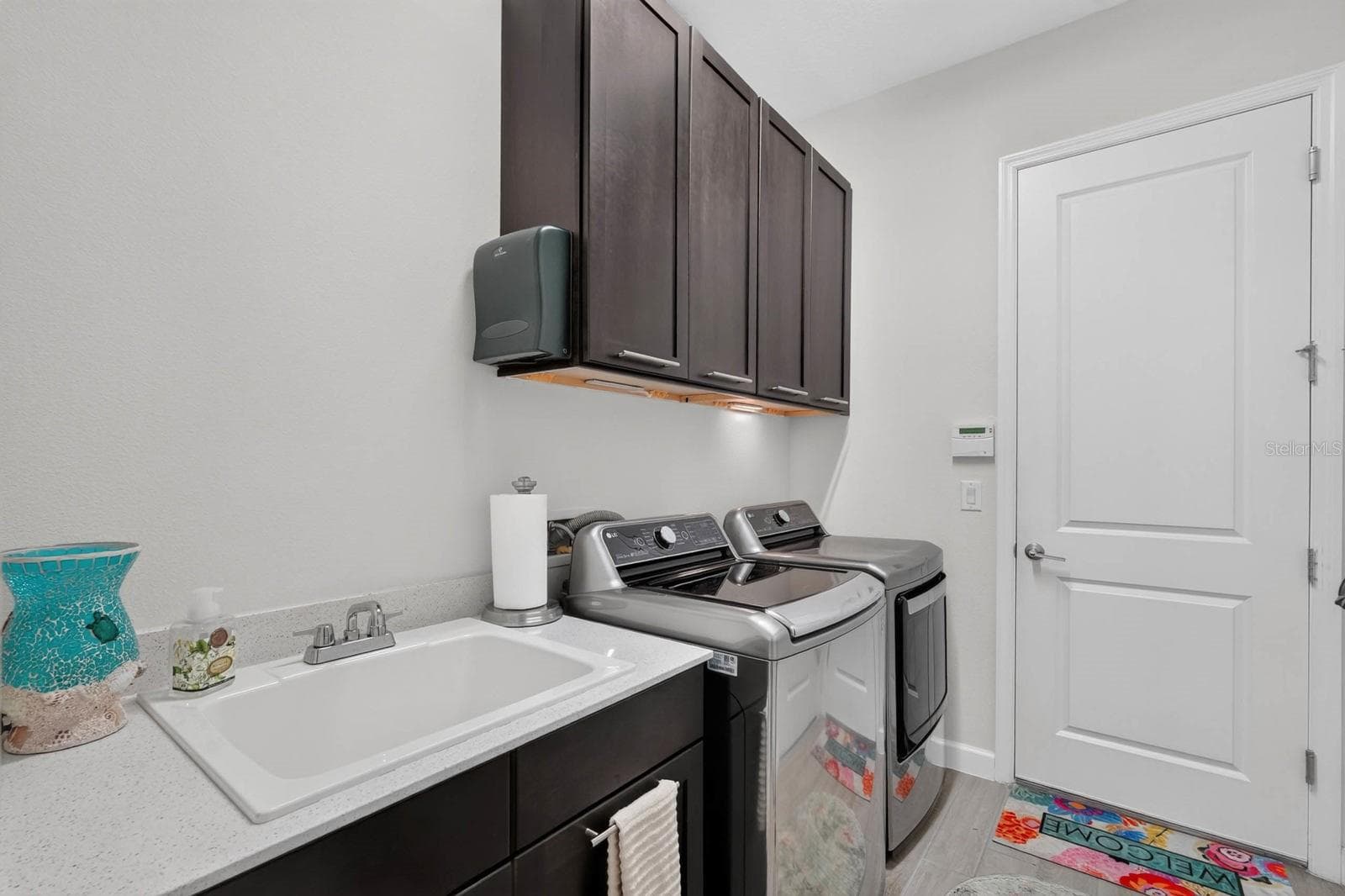 Laundry room has sink with cabinet plus overhead cabinetry and a storage closet - 36 NEW WATER OAK DR, PALM COAST