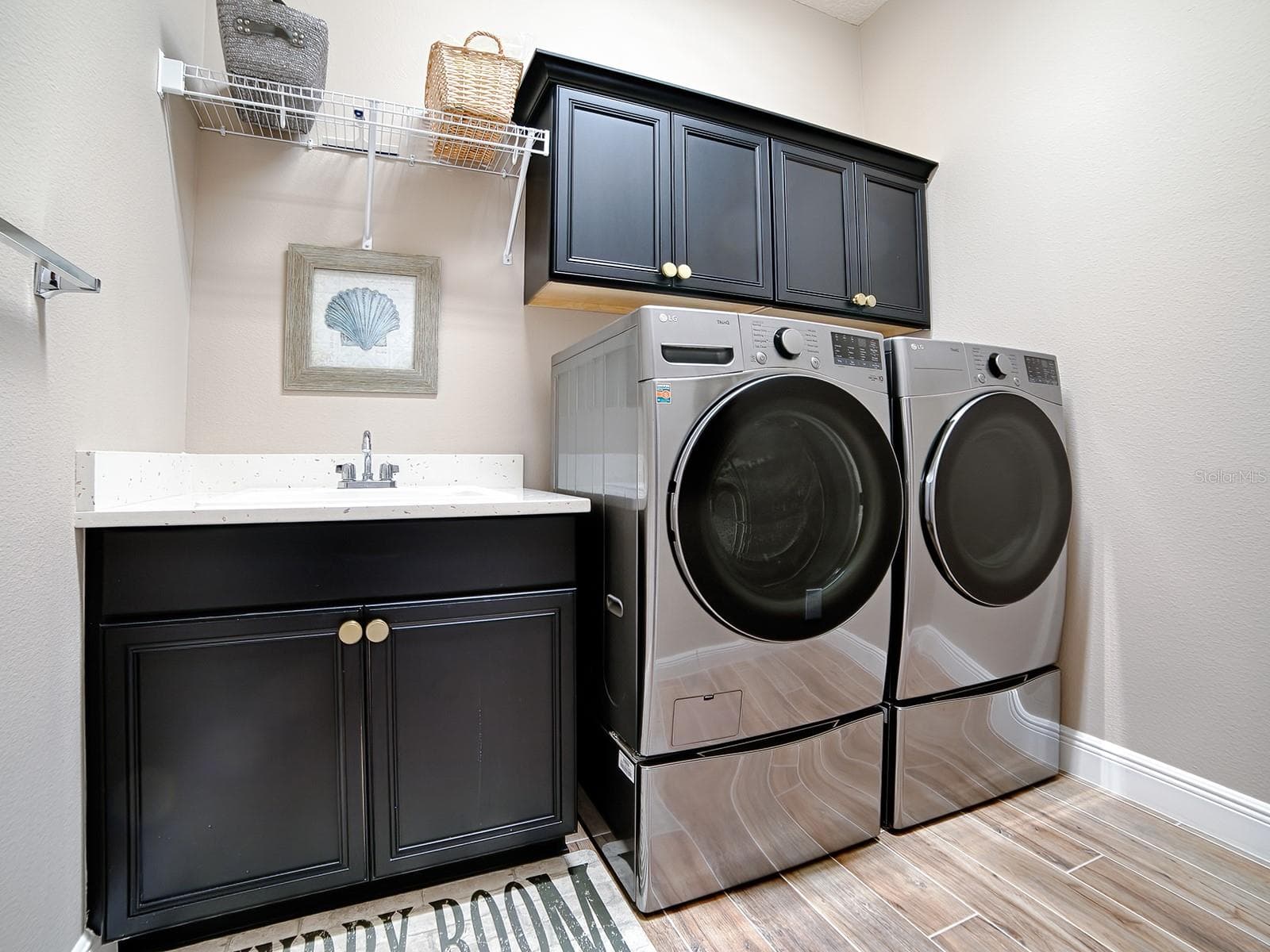THE LAUNDRY ROOM IS IN THE HALLWAY THAT LEADS TO THE 2ND GUEST SUITE. QUARTZ COUNTERTOPS, BUILT-IN SINK AND EXTRA CABINETS FOR MORE STORAGE SPACE. THE FRONT LOAD WASHER AND DRYER DO CONVEY. - 3075 LICCIARDELLO PATH, THE VILLAGES