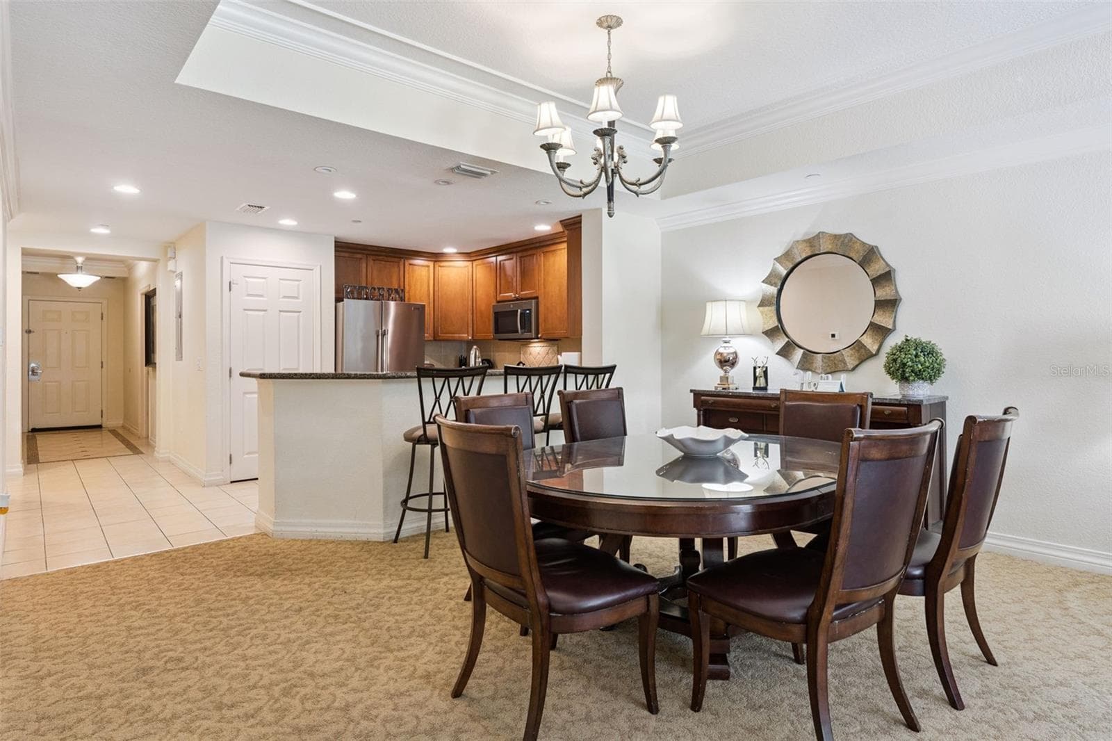 Dining Room & Entryway: Dedicated dining area situated off the main foyer, complete with overhead chandelier lighting and adjacent access to the kitchen counter bar. - 7656 WHISPER WAY #102, REUNION