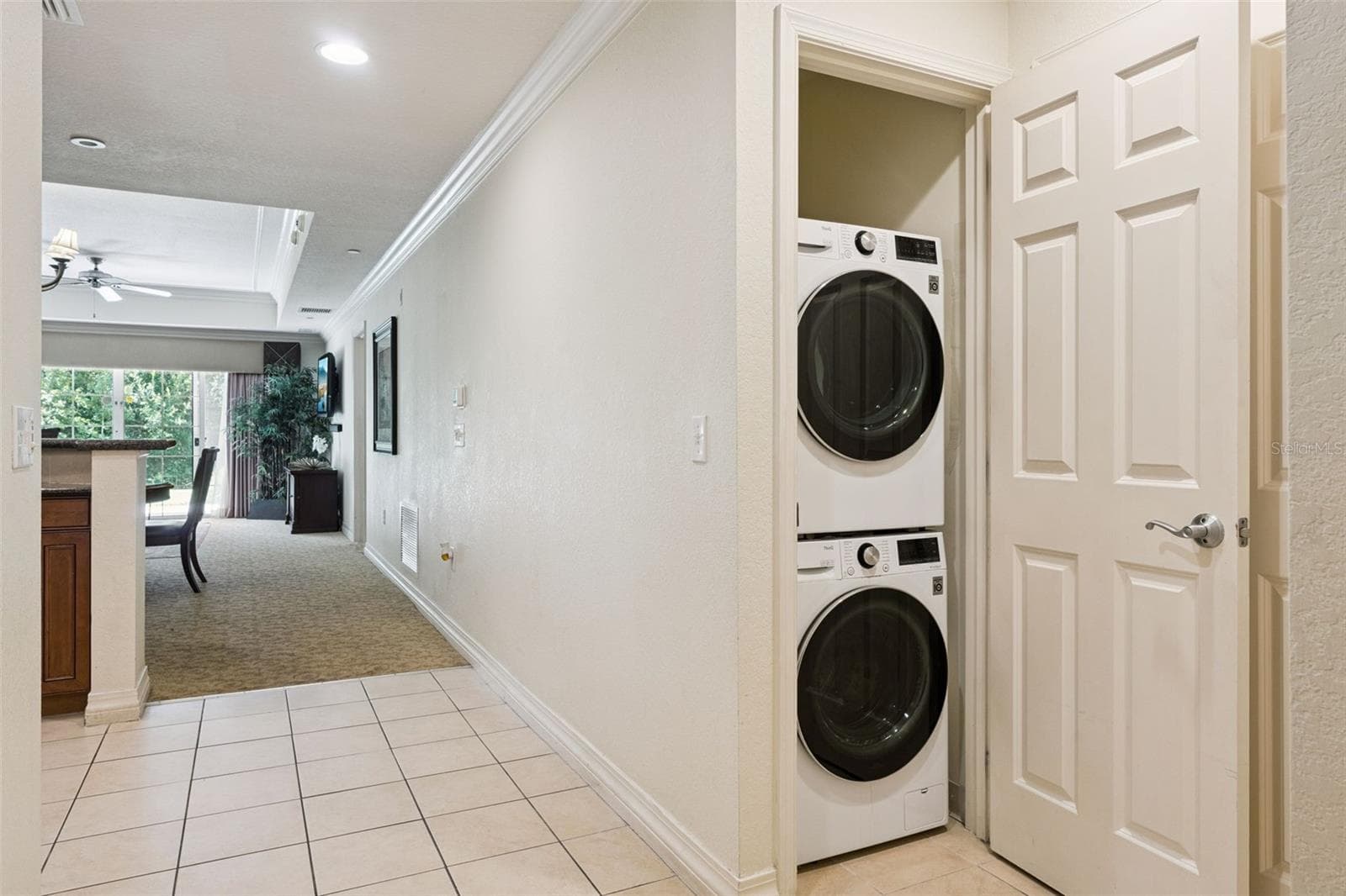 Laundry Closet: Dedicated hallway laundry closet equipped with a modern stacked washer and dryer set. - 7656 WHISPER WAY #102, REUNION