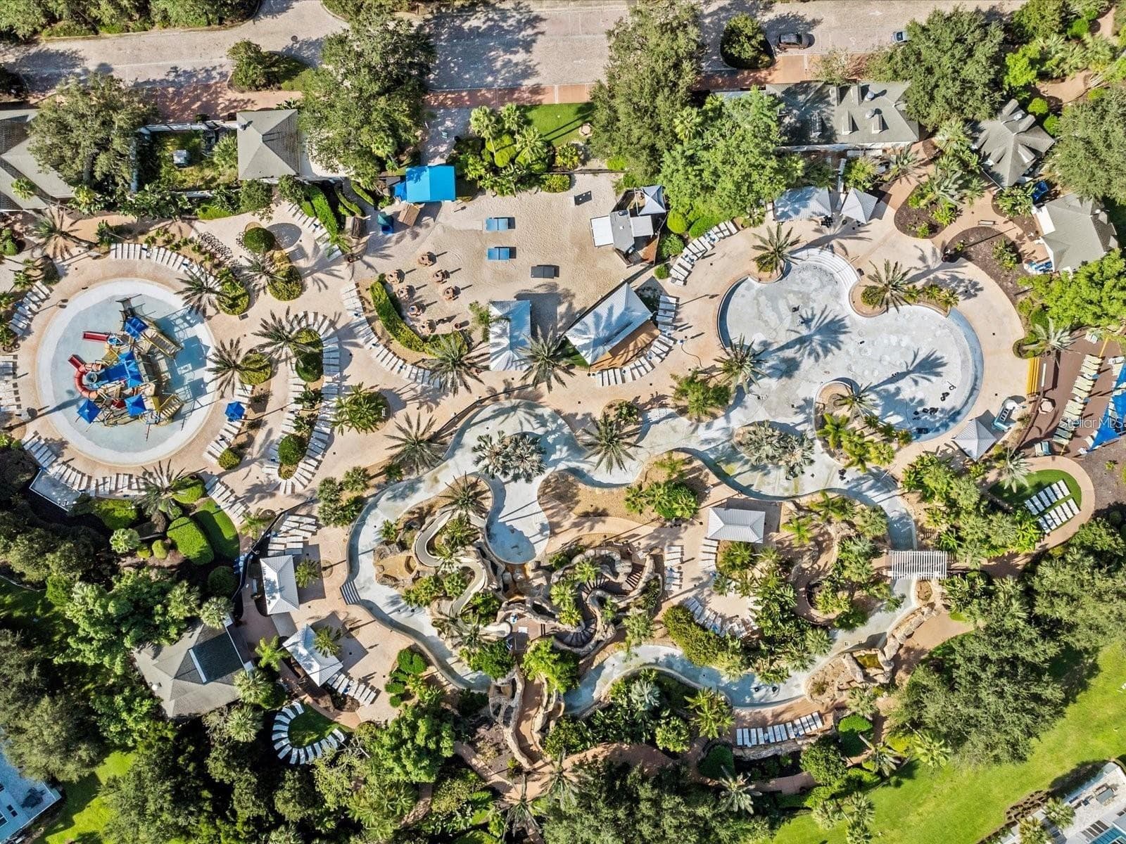 Overhead View of Water Park Complex: Complete top-down drone perspective of the expansive water park, featuring lazy river loops, splash zone, sunbathing decks, and cabanas. - 7656 WHISPER WAY #102, REUNION
