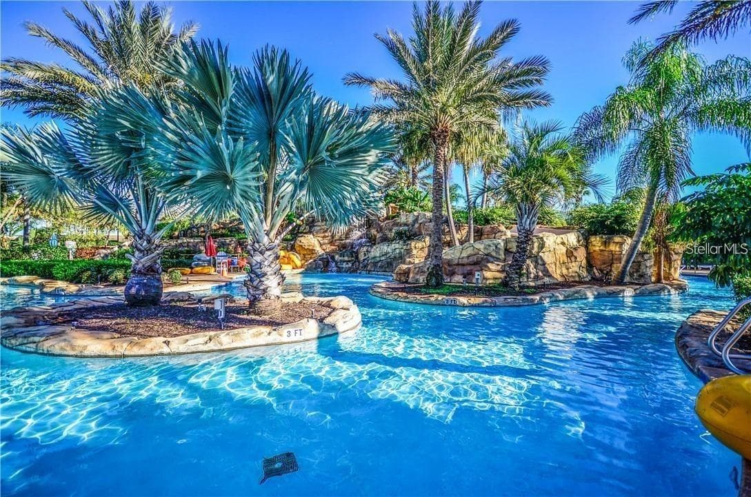 Tropical Lazy River & Lagoon: Serene lazy river and lagoon pool winding past natural rock waterfalls and lush tropical palms. - 7656 WHISPER WAY #102, REUNION