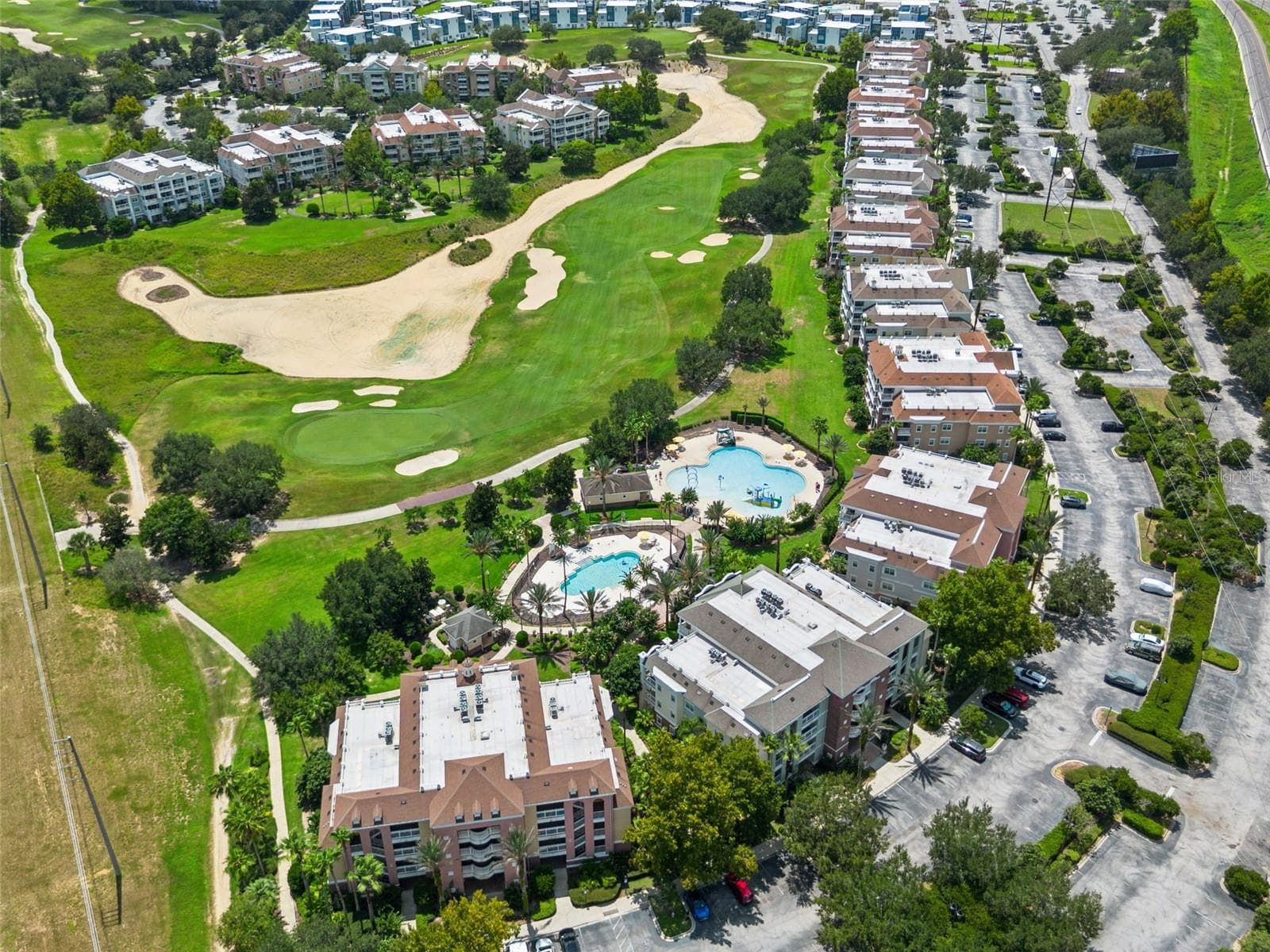 Resort Grounds & Golf Course: Broad aerial overview featuring the resort pool area, adjacent golf course greens, manicured landscaping, and surrounding community. - 7656 WHISPER WAY #102, REUNION