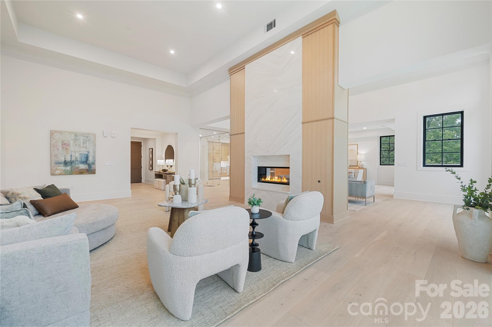 The striking two-sided fireplace with floor-to-ceiling stone and warm wood detailing anchors the main living spaces in this sophisticated and light-filled residence. - 409 Queens Road, Charlotte