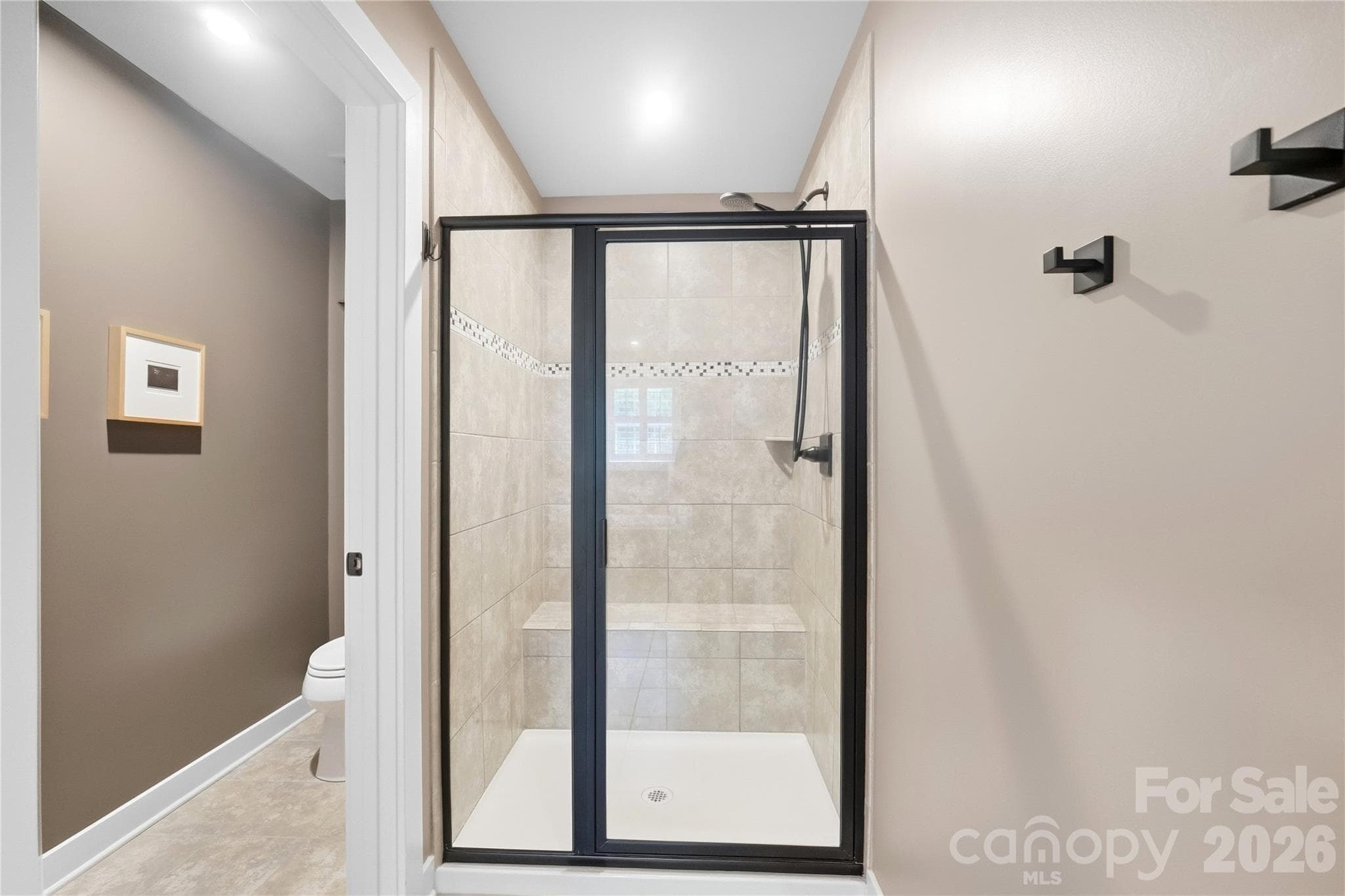 Walk-in tile shower with a built-in bench seat, plus a private water closet. - 912 Manorwood Drive, Waxhaw