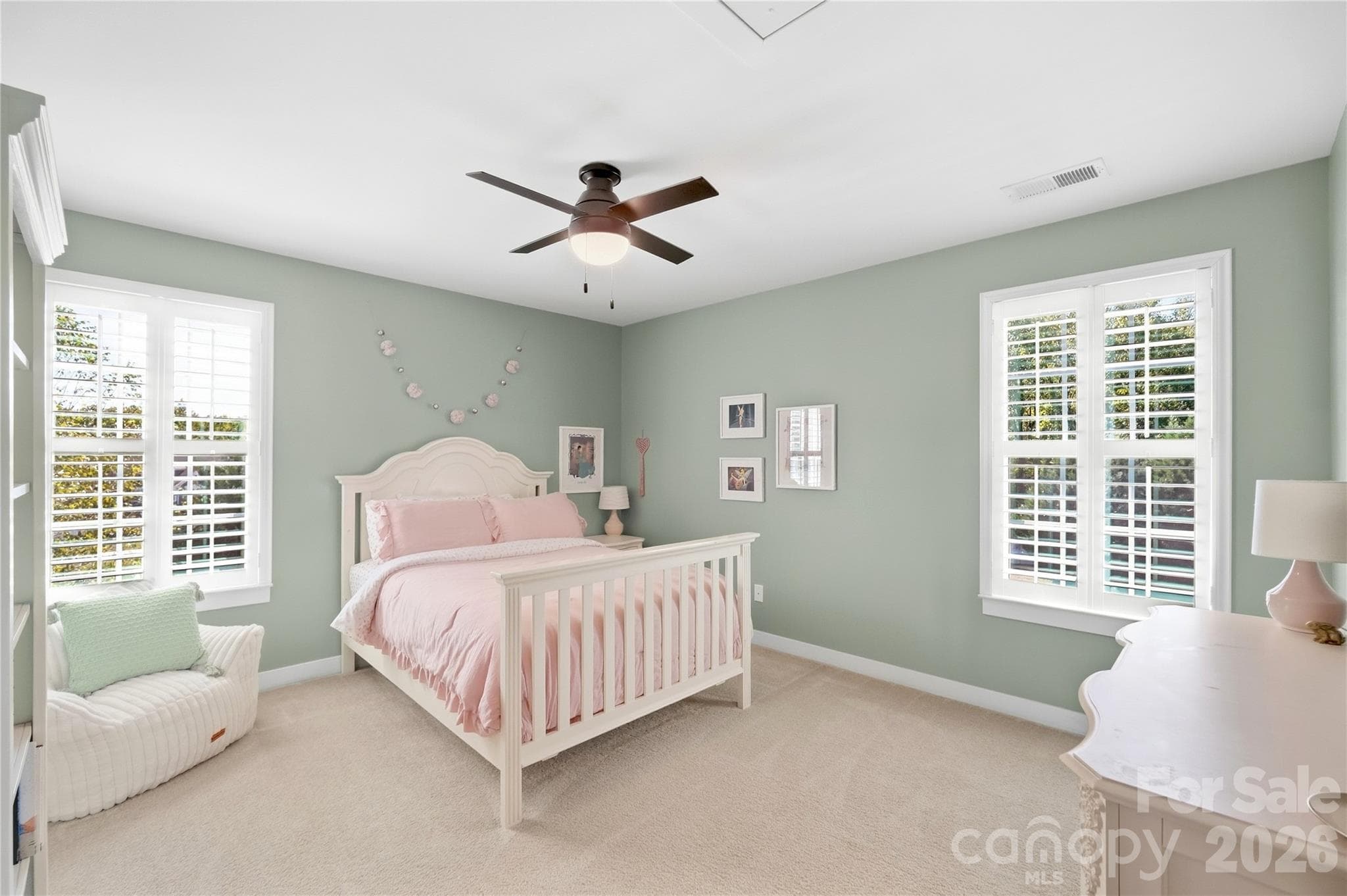 Bedroom 2 with windows on two walls, plantation shutters, and a ceiling fan. - 912 Manorwood Drive, Waxhaw