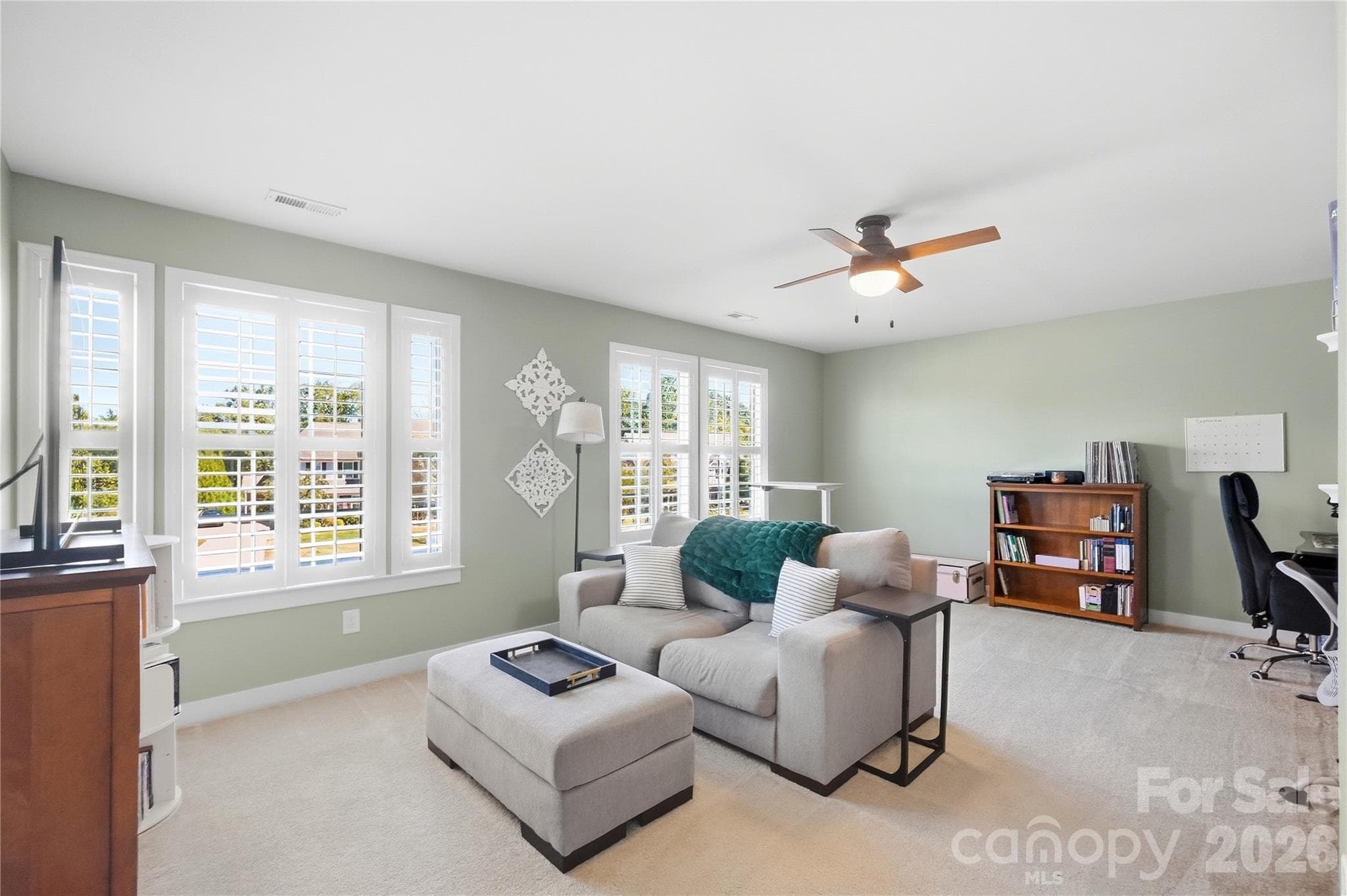 Bonus room with a door, windows on two walls, plantation shutters, and a ceiling fan, versatile enough for a media or theater room or a play space. - 912 Manorwood Drive, Waxhaw