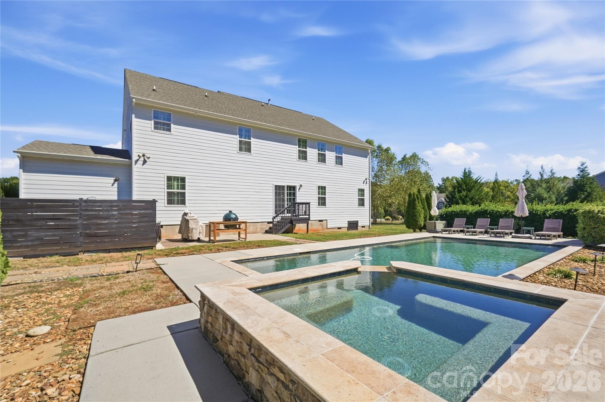 Raised stone spa with built-in seating, overlooking the pool and the rear patio. - 912 Manorwood Drive, Waxhaw