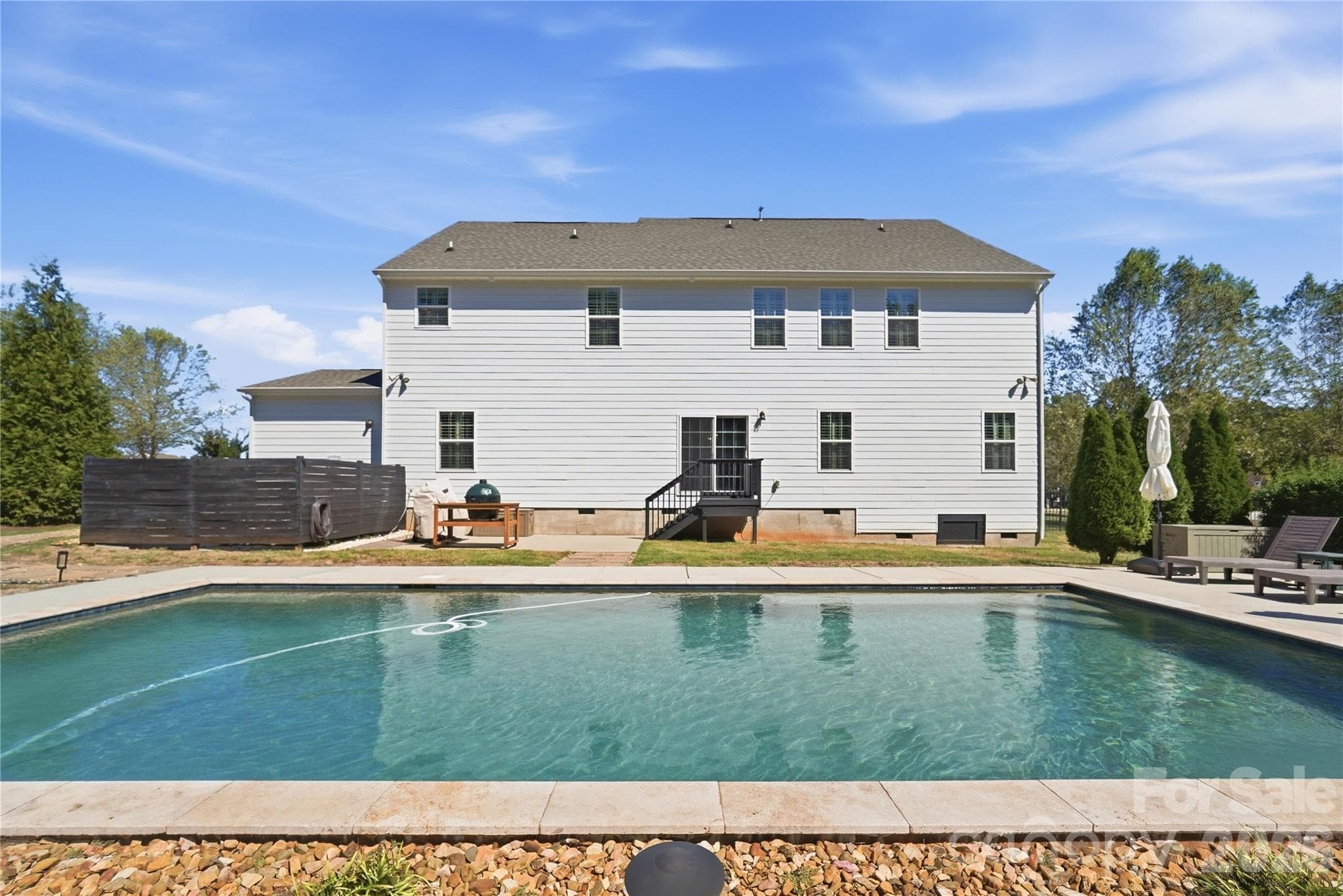 Heated saltwater pool with stone coping, set against the rear of the home and a private patio area. - 912 Manorwood Drive, Waxhaw
