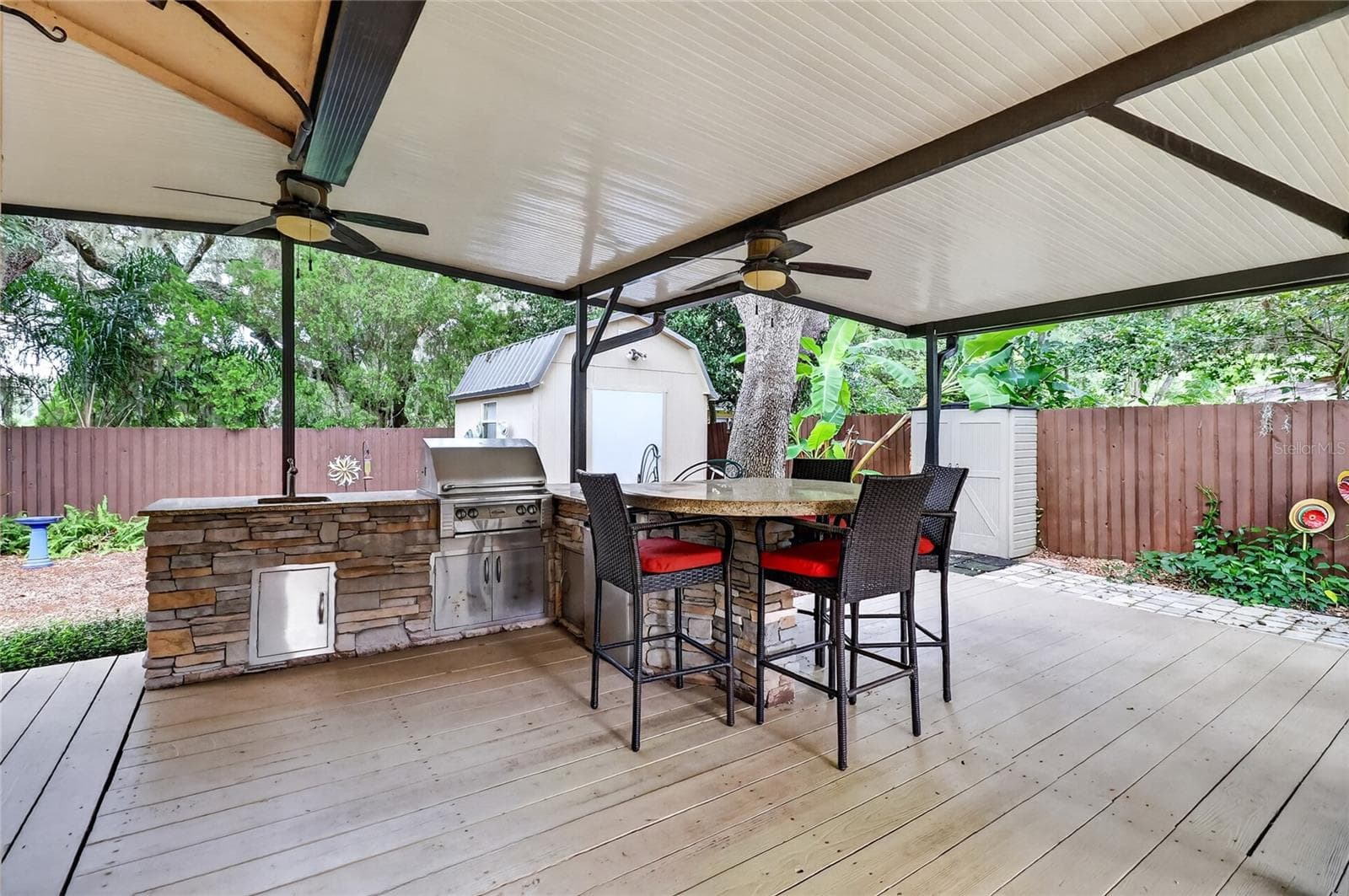 Outdoor Kitchen with a granite-topped bar, built-in gas grill, ceiling fans, and a gas fire pit. - 3011 LAKE ELLEN DR, TAMPA