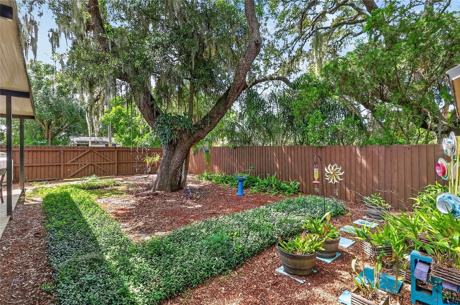 Backyard is surrounded by mature oaks, tropical landscaping, and a colorful garden. - 3011 LAKE ELLEN DR, TAMPA