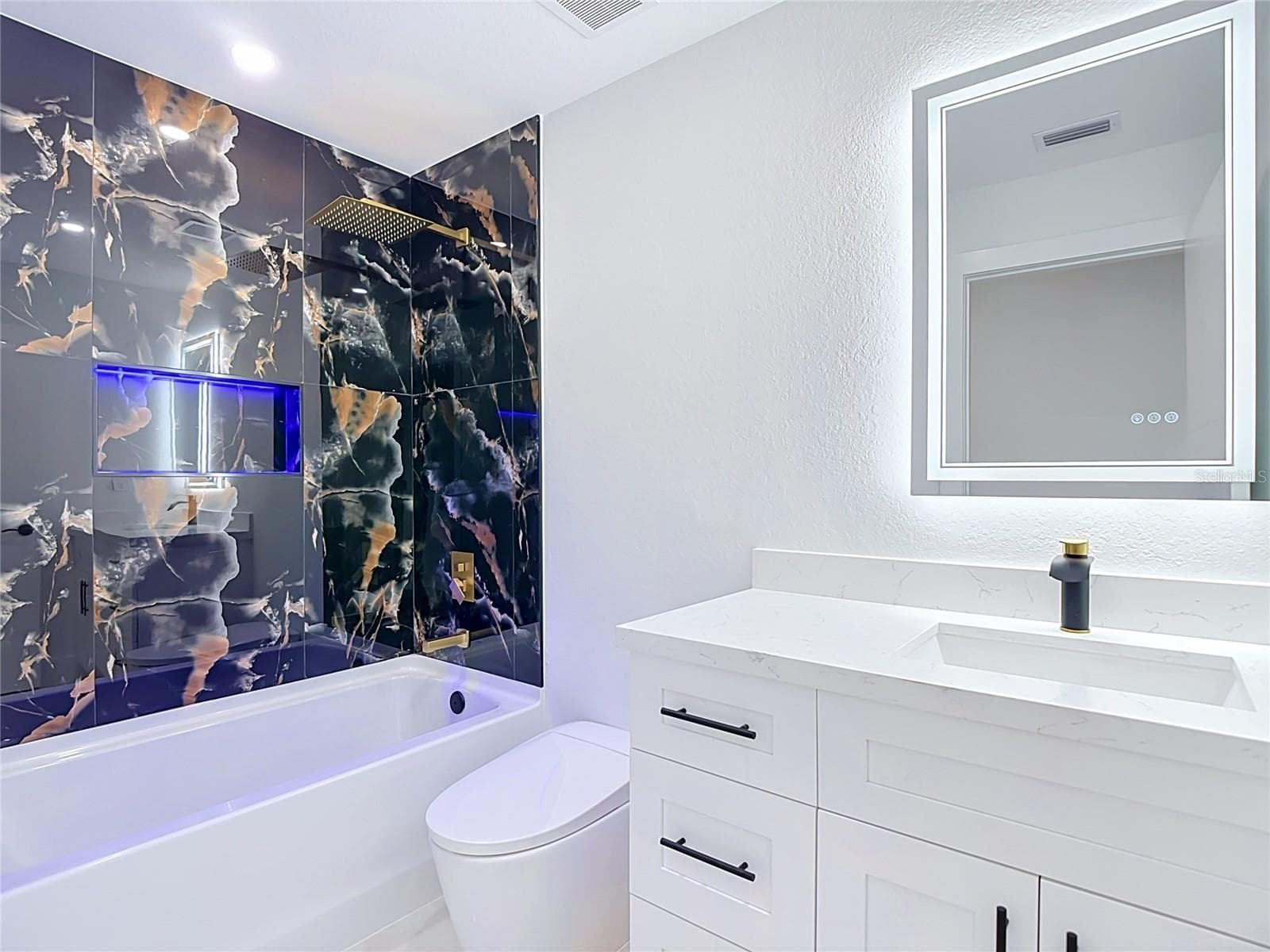 2nd bathroom features bathtub with lit cubby, smart mirror, toilet with bidet and a single vanity. - 3613 NW 47TH LN, CAPE CORAL