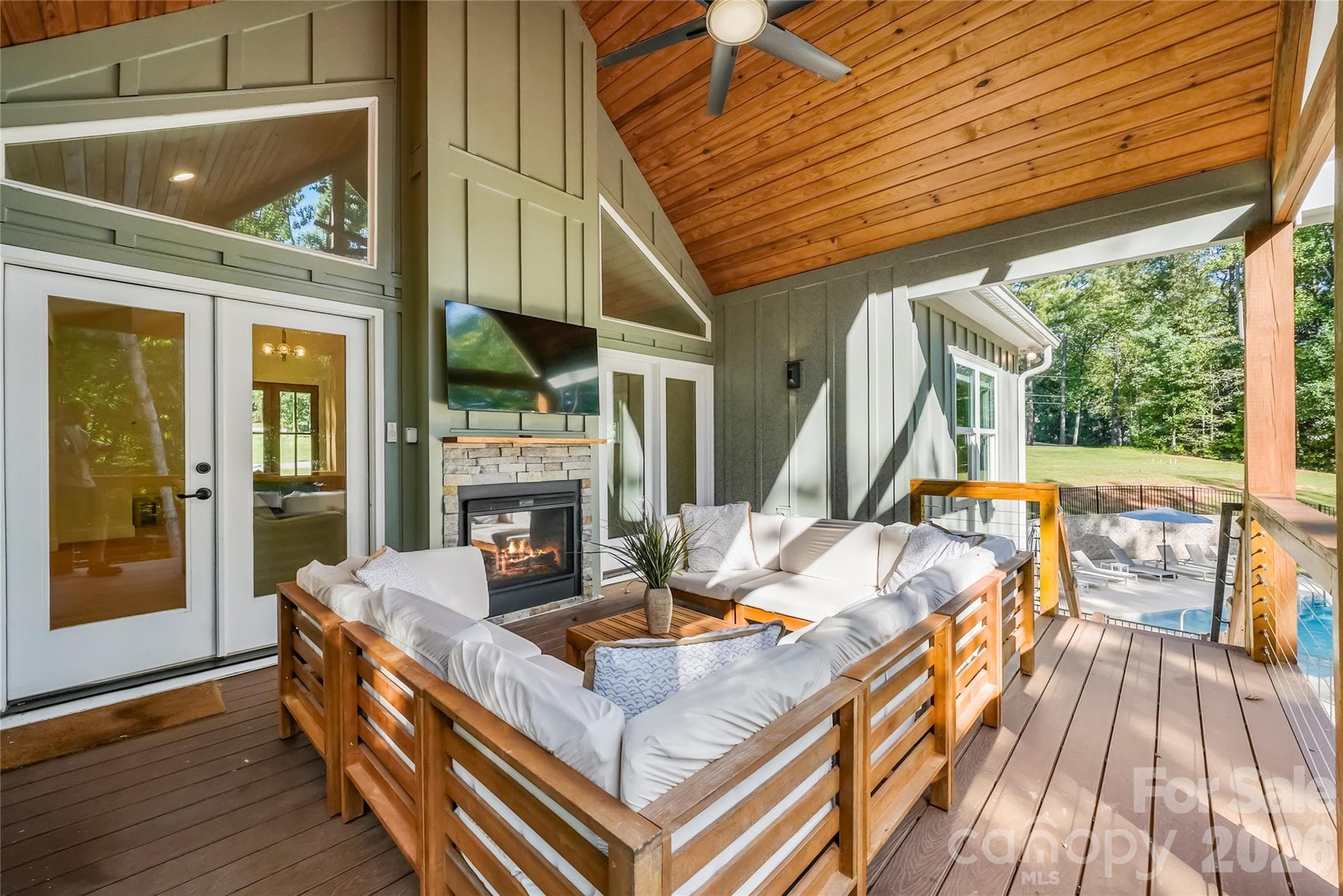 With a fireplace, comfortable seating, and the pool just steps away, this covered porch is an outdoor extension of the living space. - 143 Hideaway Lane, Mooresville