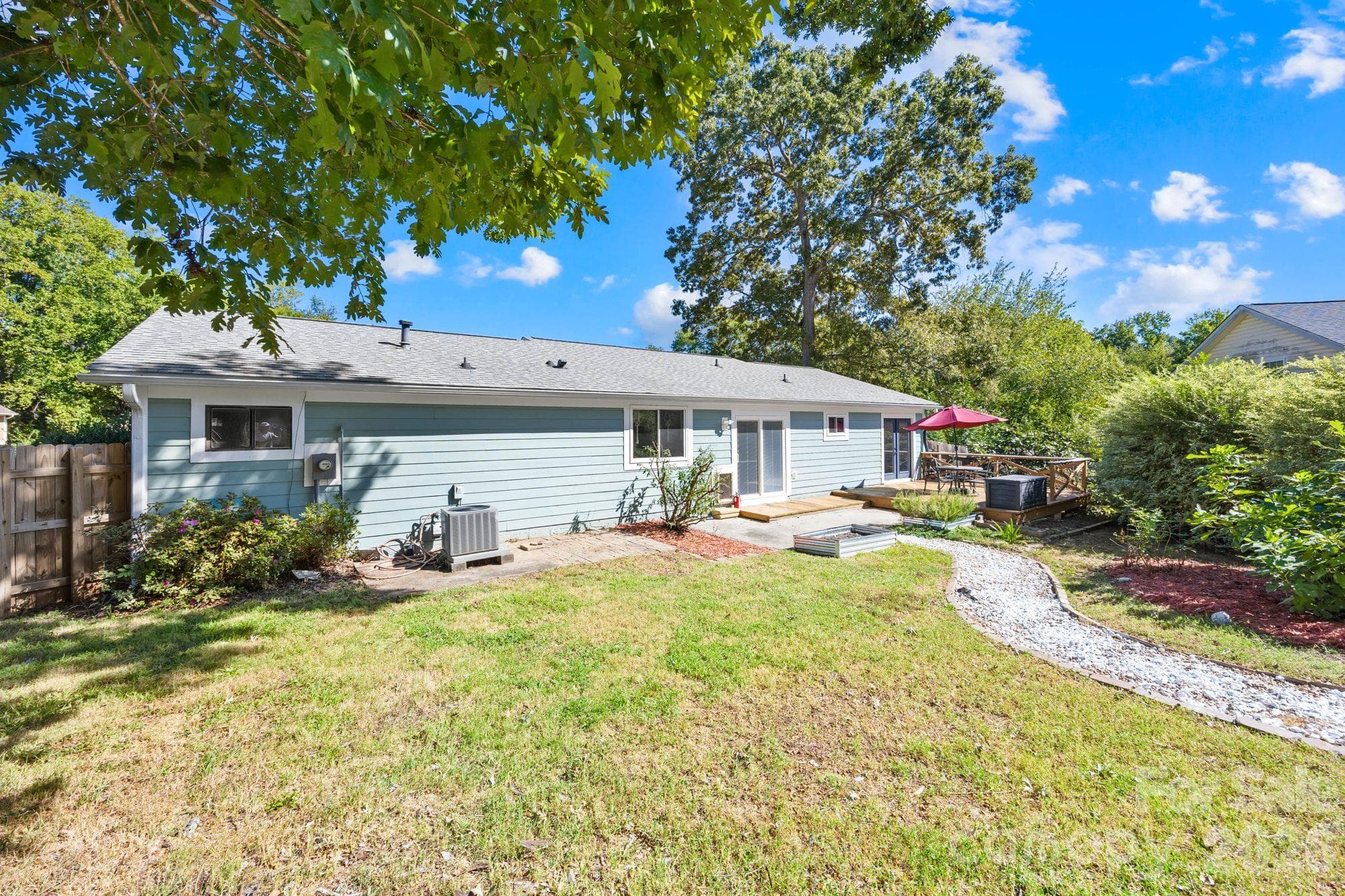 Backyard on a 0.34-acre corner lot with mature fruit trees, raised garden beds and a gravel garden path at an East Charlotte ranch home - 4900 Cricklewood Lane, Charlotte