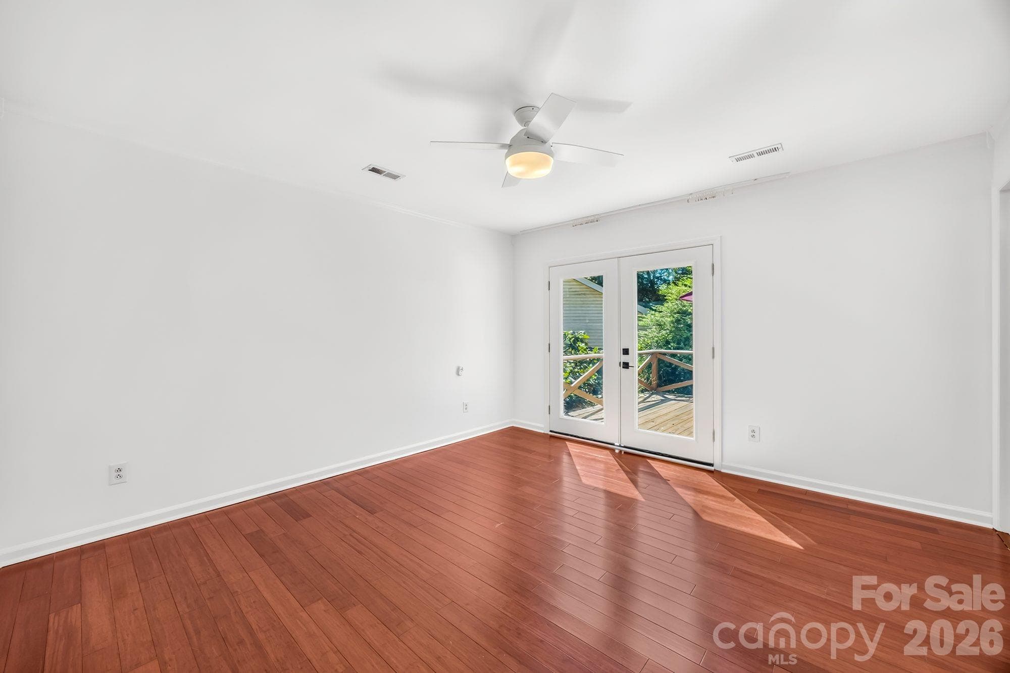 Primary bedroom with ceiling fan and French doors to the backyard at 4900 Cricklewood Ln, Charlotte - 4900 Cricklewood Lane, Charlotte