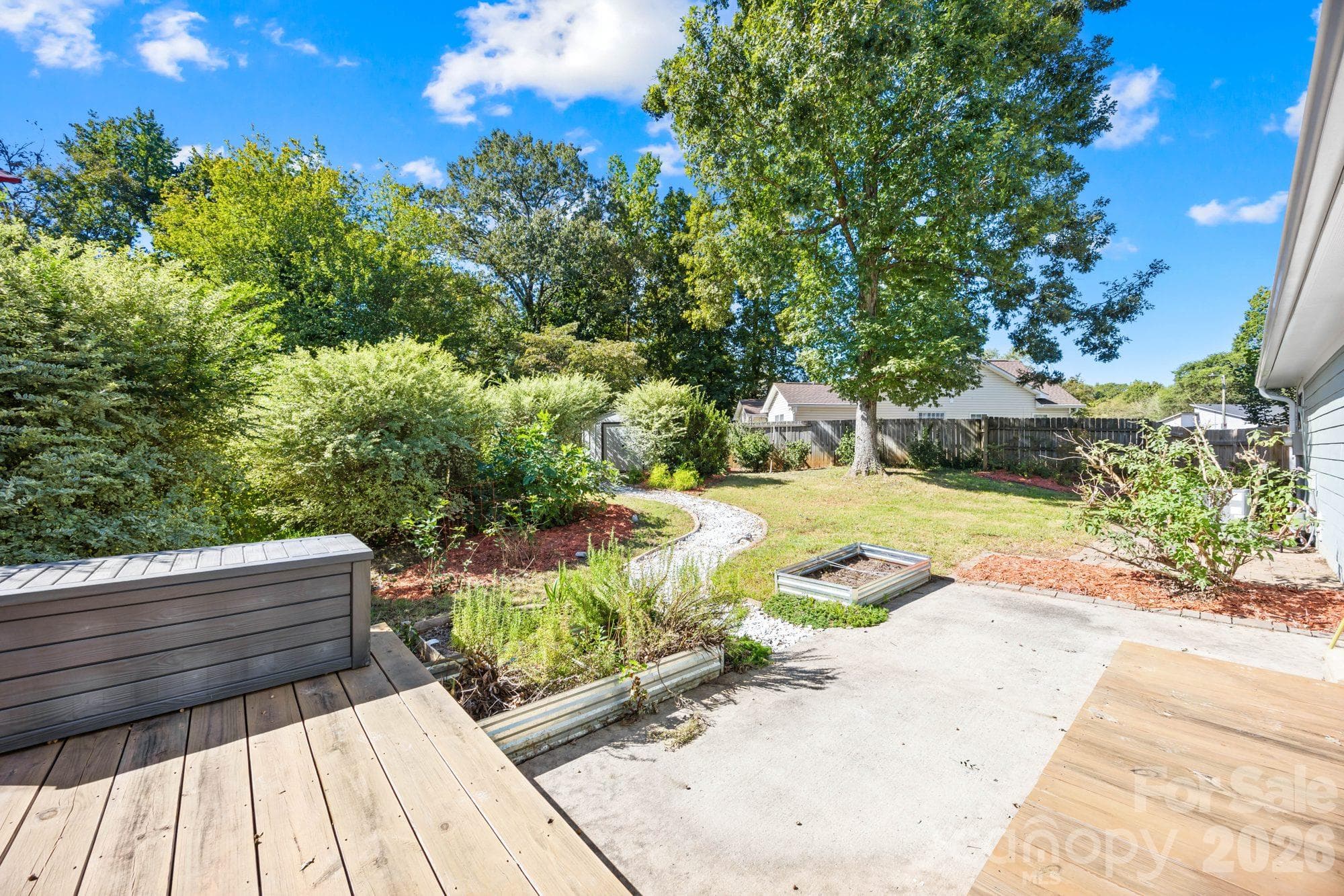 Back deck stepping down to a patio and landscaped backyard at 4900 Cricklewood Ln, East Charlotte - 4900 Cricklewood Lane, Charlotte
