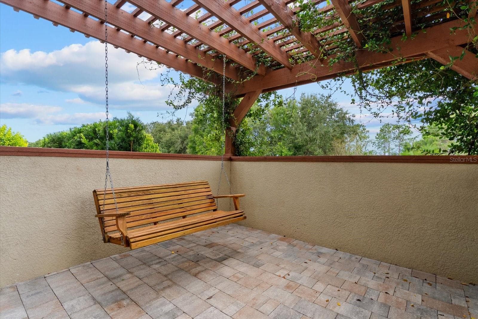 A porch swing and vine covered trellis adorn the side patio off the dining room - 520 RYE RD NE, BRADENTON