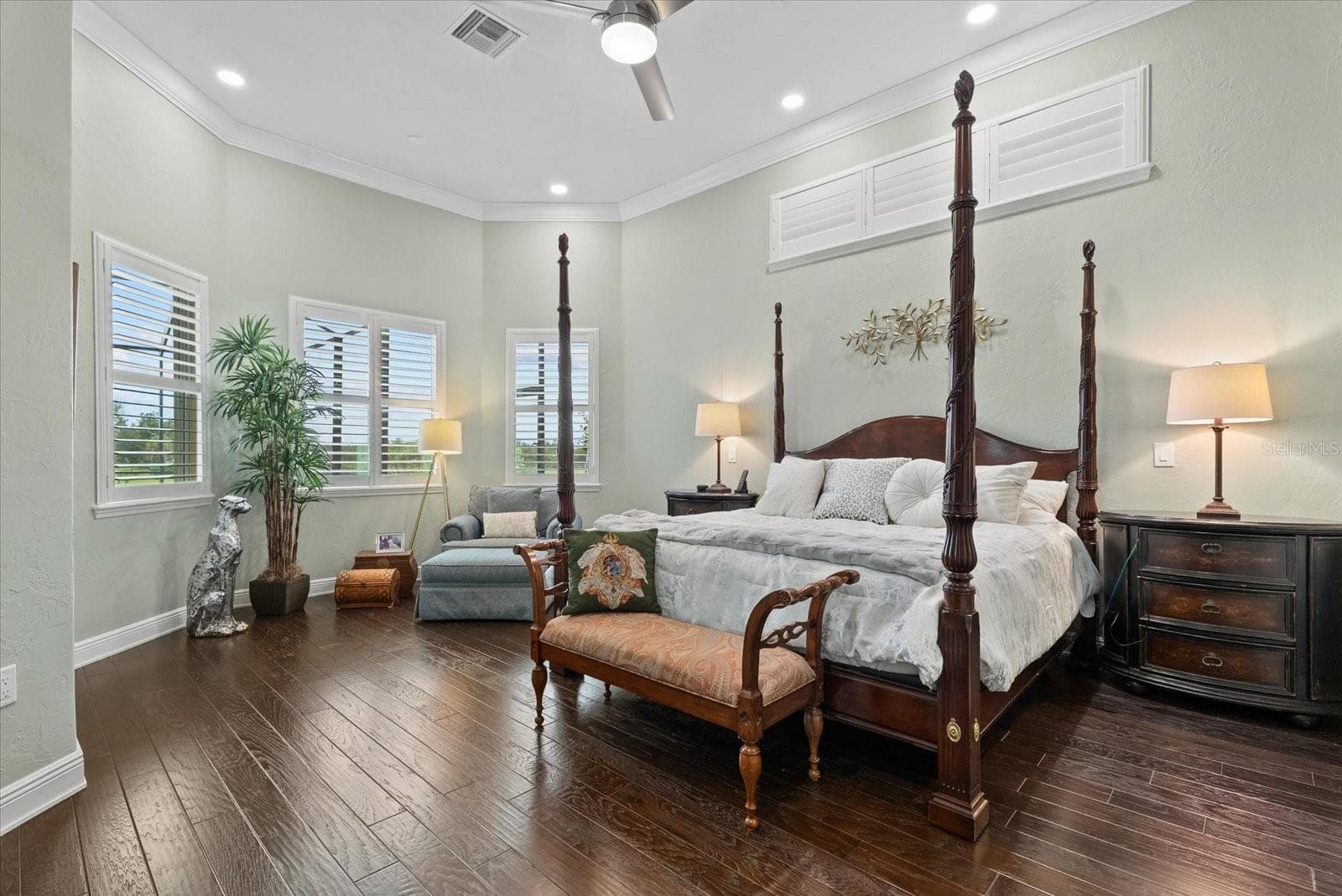 Also on the first floor is a spacious primary suite with high ceilings, wood floors, clerestory windows over the bed, crown molding and an entry door to an outside lounge space - 520 RYE RD NE, BRADENTON