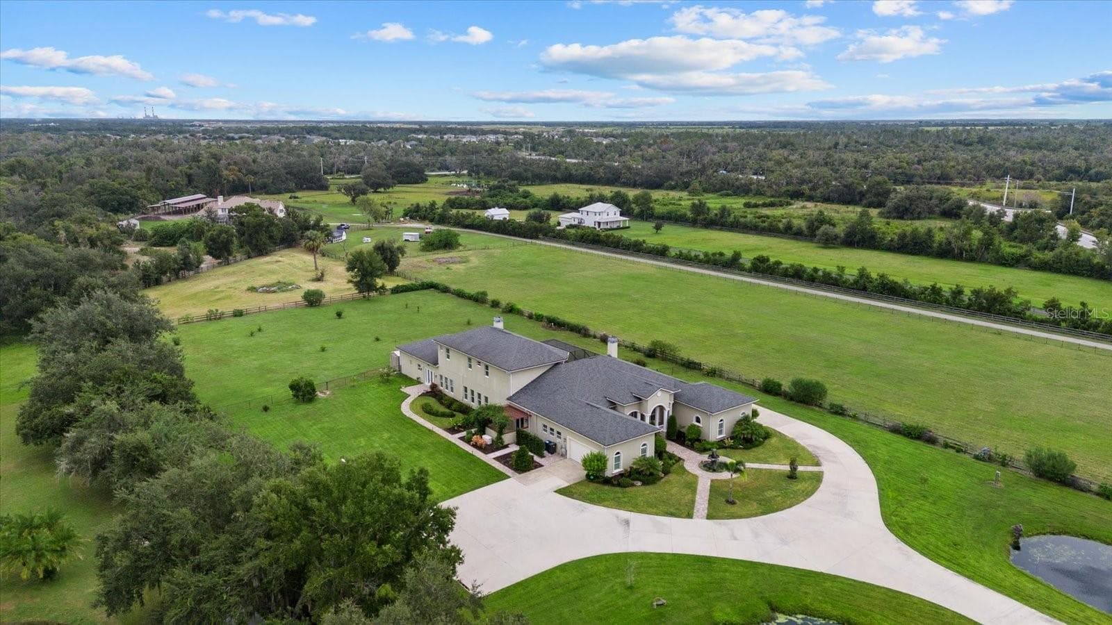 This drone shot shows the main house, front pasture behind the home and a triangle shaped pasture beyond it. - 520 RYE RD NE, BRADENTON