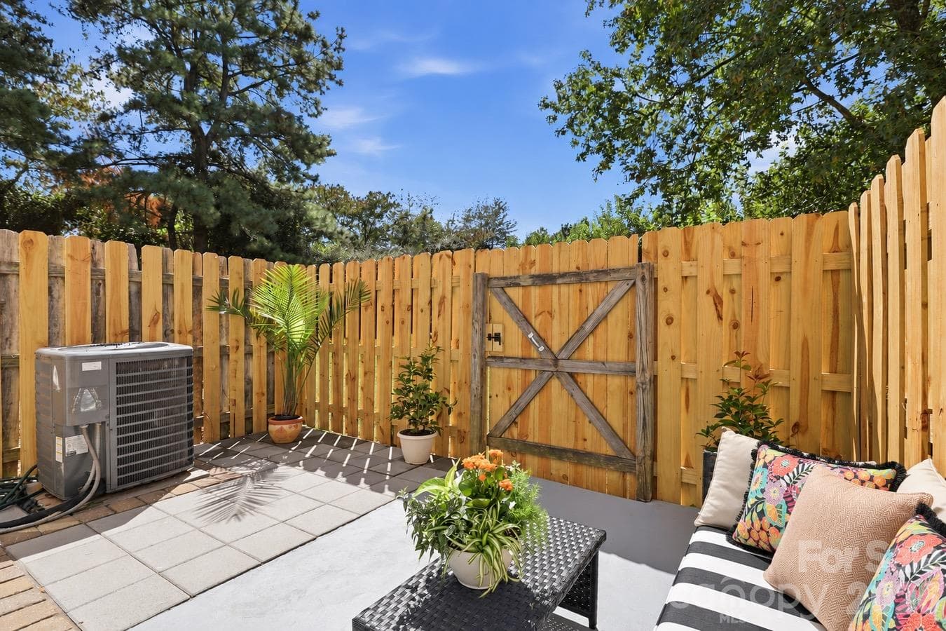 Settle into this inviting outdoor nook, framed by wood fencing and colorful accents. - 3858 Mosscroft Lane, Charlotte
