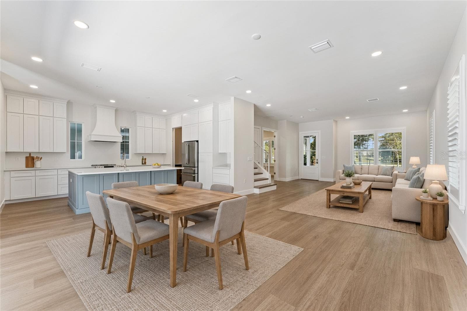 Virtually Staged - An open living area connects to the kitchen, with a blue island and coordinated white cabinetry. - 3456 FAIRWAY LN, ORLANDO