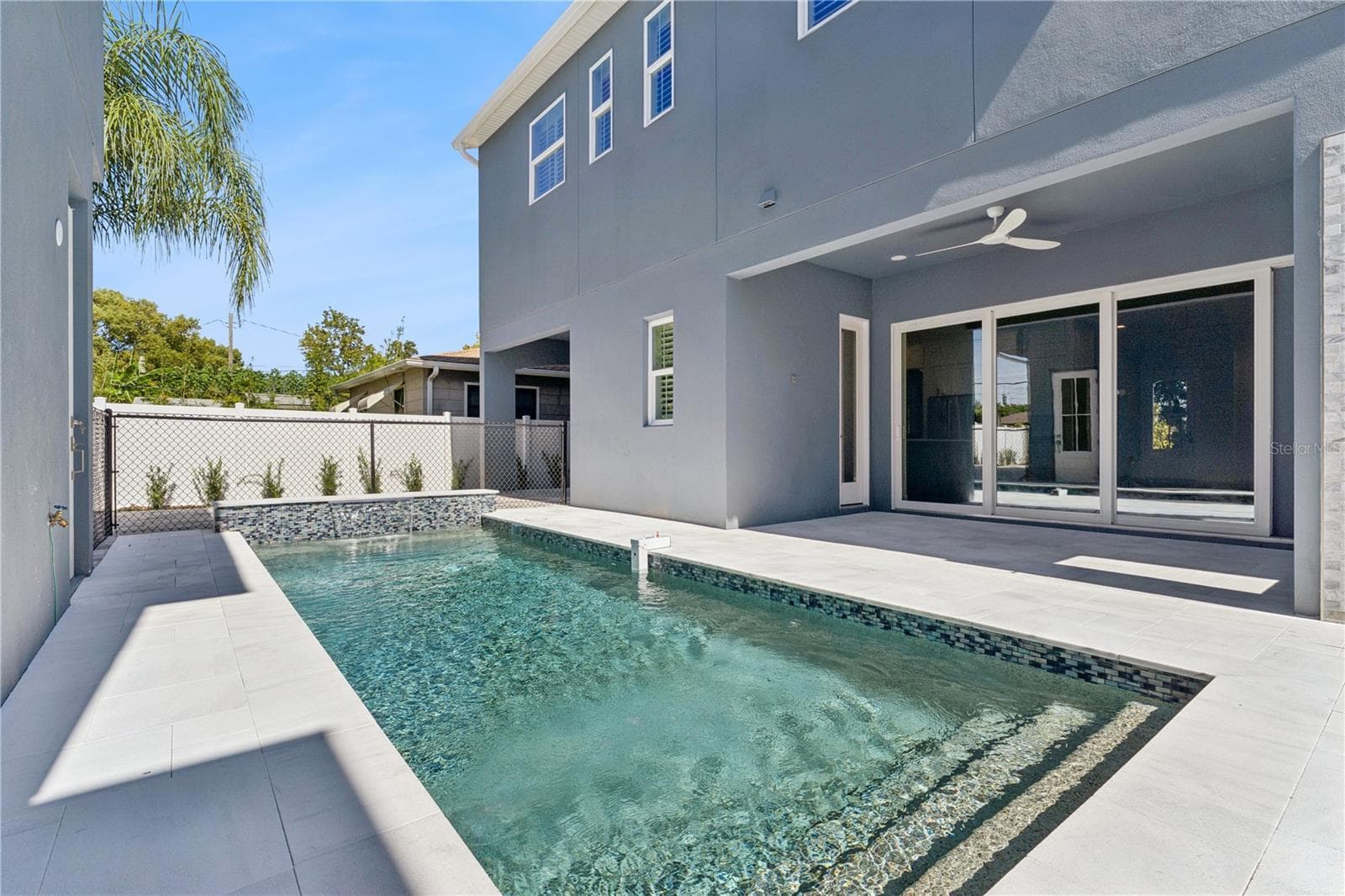 The pool sits beside a paved deck and covered rear patio, creating an inviting outdoor setting. - 3456 FAIRWAY LN, ORLANDO