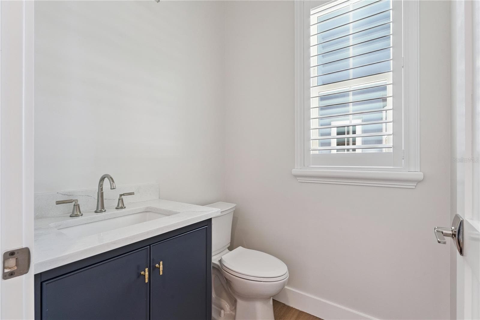 A navy vanity, light countertop, and shuttered window give this powder room a crisp finish. - 3456 FAIRWAY LN, ORLANDO