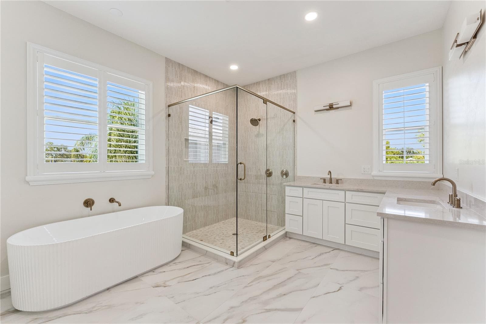 A freestanding tub, glass-enclosed shower, and two sinks define this spacious bathroom. - 3456 FAIRWAY LN, ORLANDO