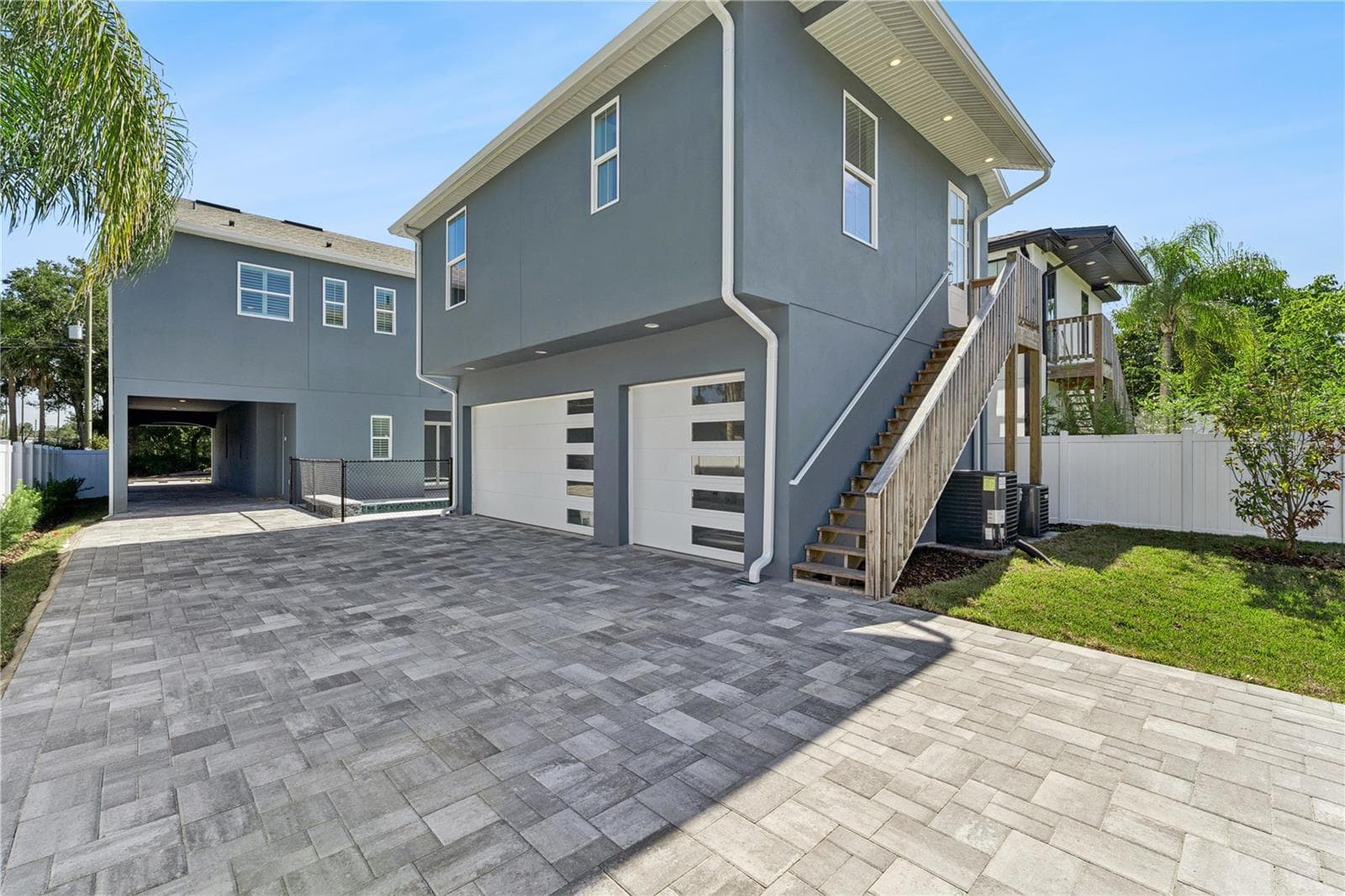 The rear garage has two garage doors, an exterior staircase, and a paved parking area. - 3456 FAIRWAY LN, ORLANDO