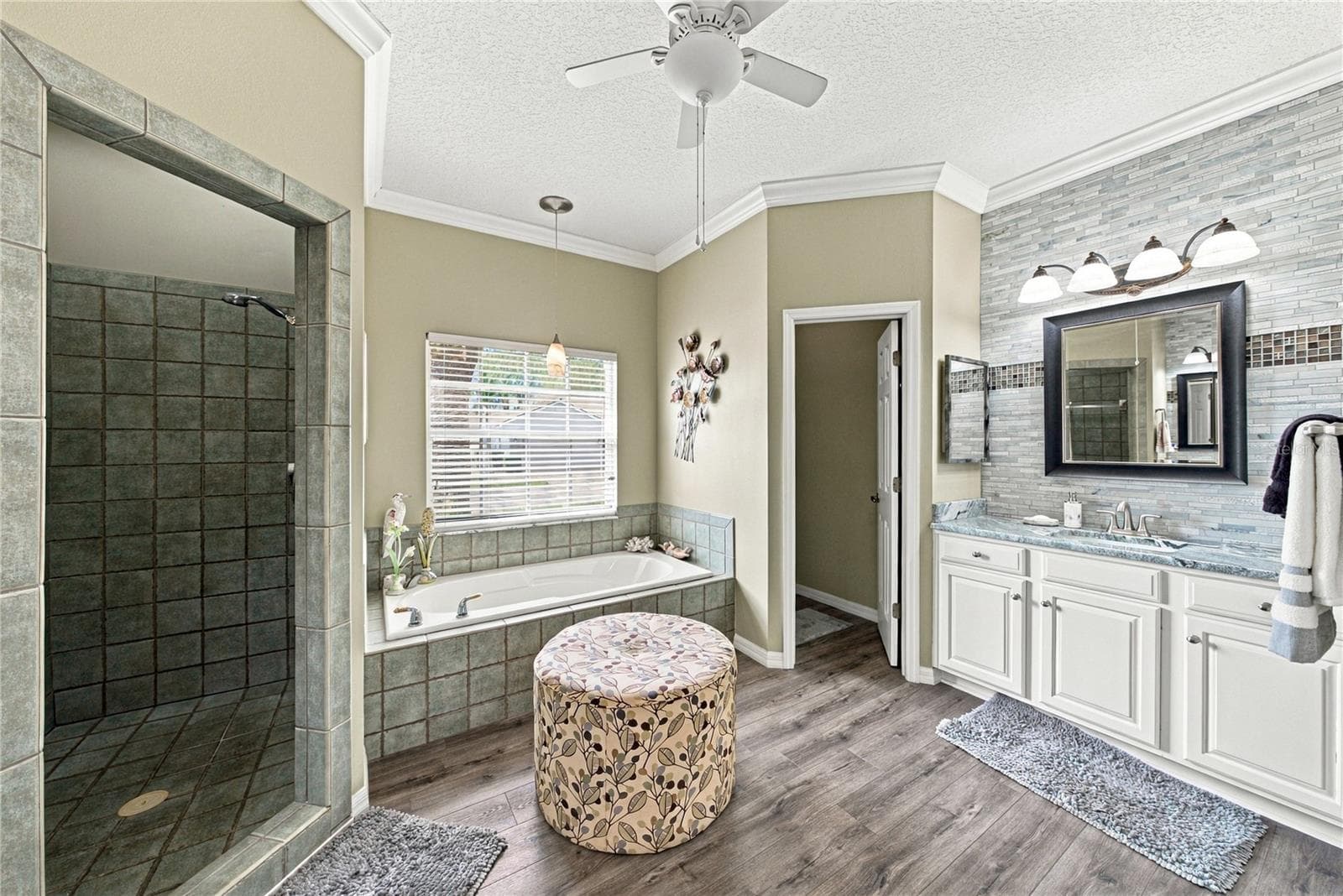 The primary bath has stone accent walls, crown molding, ceiling fan with light, and a privacy toilet room. - 4232 DORNOCH DR, LAKE WALES