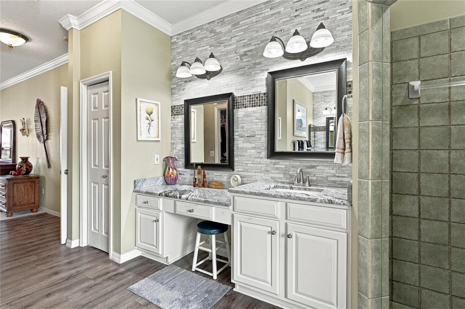 The east vanity has stone countertops, a makeup area, elevated sink, stone wall with accents, upgrades lighting and plumbing fixtures. - 4232 DORNOCH DR, LAKE WALES