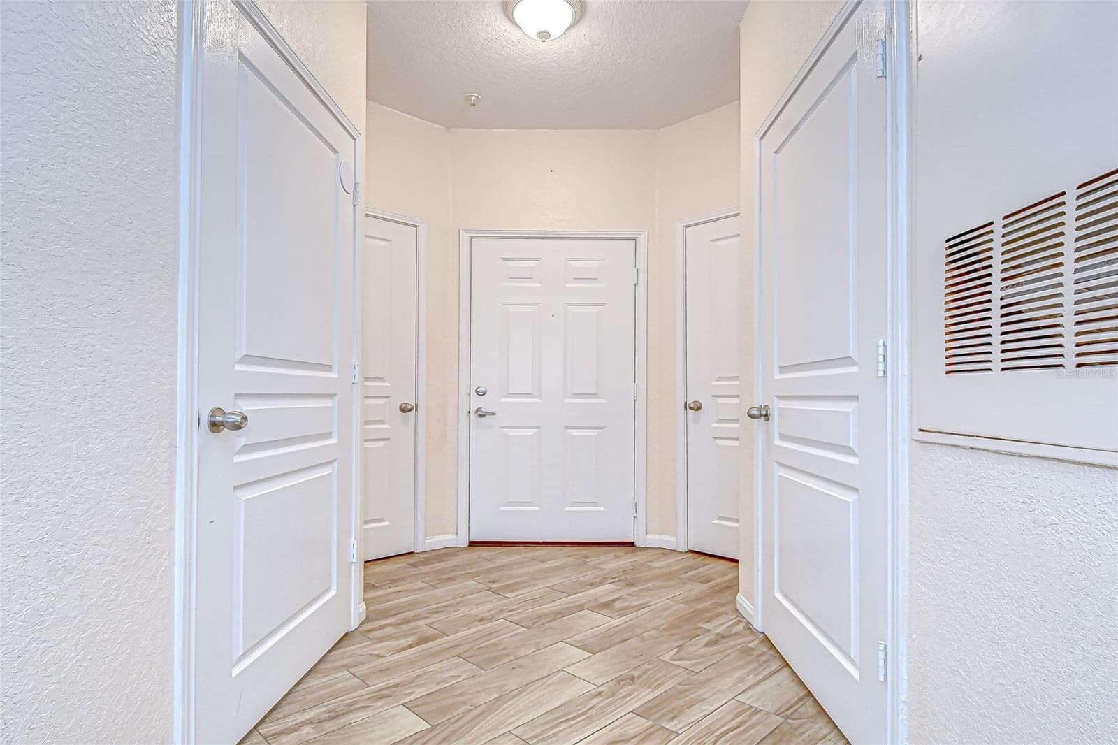 Bright and functional foyer features wood-look flooring, multiple surrounding storage or utility closets, and an open entryway leading into the main living areas. - 5125 PALM SPRINGS BLVD #3104, TAMPA