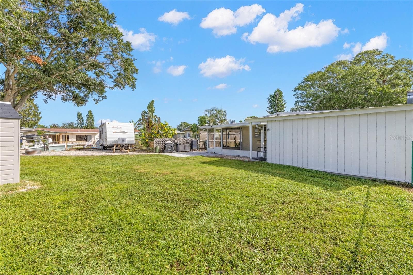 The oversized 11,800-square-foot (.27-acre) property continues into a broad backyard with generous lawn space, fencing for added separation, and plenty of room for pets, play, gardening, or outdoor projects. - 332 WESTWINDS DR, PALM HARBOR