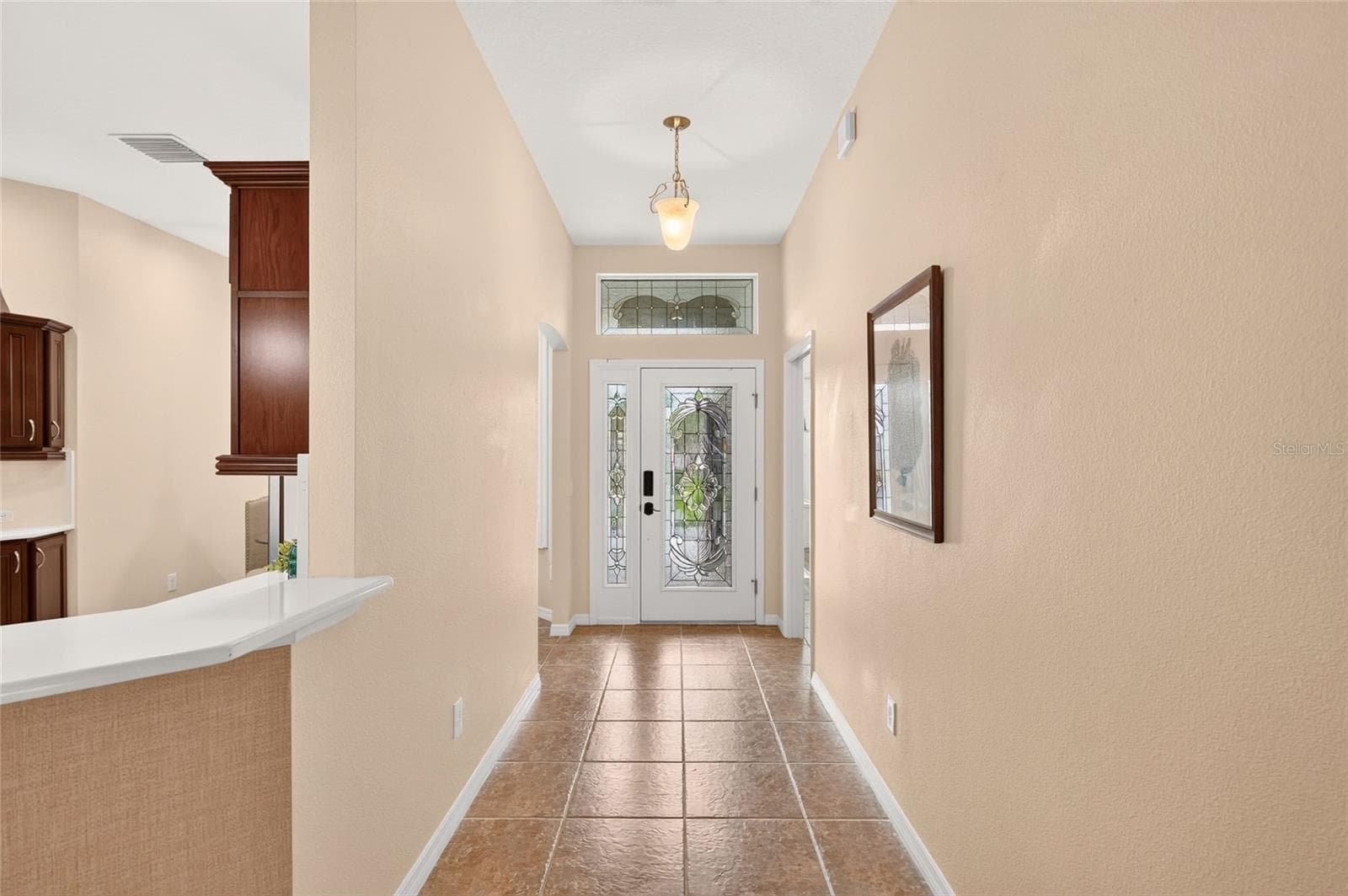 An inviting FOYER with warm wood-look flooring and decorative pendant lighting welcomes you home, opening to the kitchen and main living spaces. - 2454 MORNING DOVE LN, THE VILLAGES