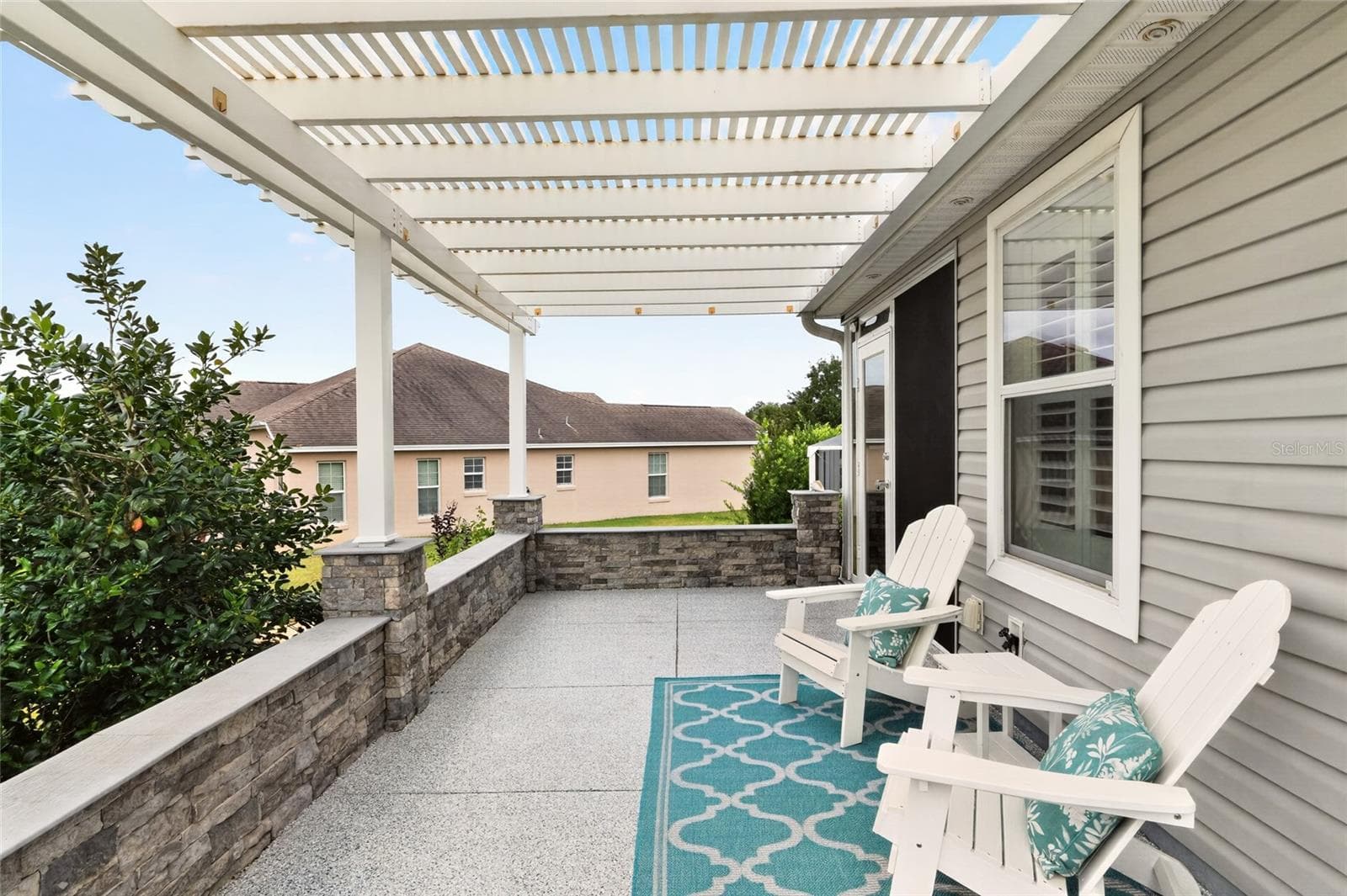 Relax beneath the charming pergola on this inviting patio, surrounded by lush landscaping—a lovely setting for morning coffee or an evening with friends. - 2454 MORNING DOVE LN, THE VILLAGES