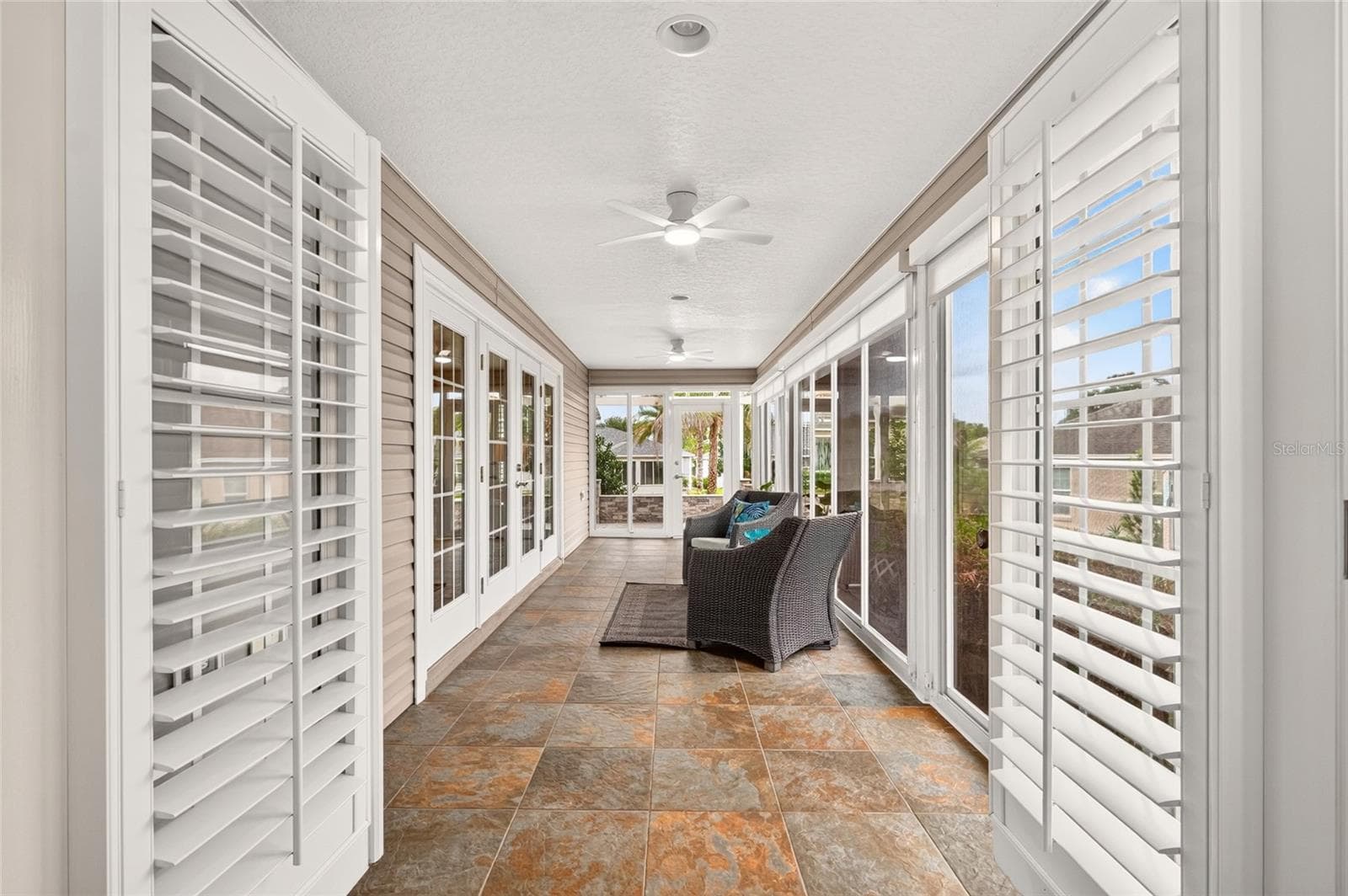 Step from the PRIMARY SUITE through the French Doors into the bright ENCLOSED LANAI, an inviting retreat for morning coffee, quiet moments, and year-round relaxation. - 2454 MORNING DOVE LN, THE VILLAGES