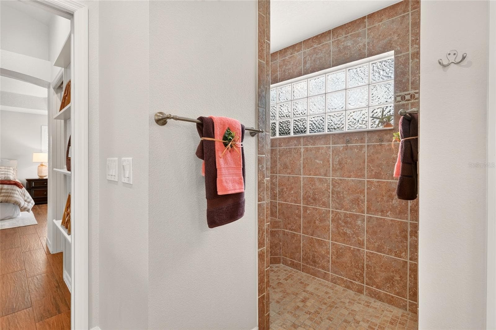 The beautifully tiled ROMAN SHOWER features a doorless entry and a GLASS-BLOCK WINDOW that welcomes natural light while maintaining privacy. - 2454 MORNING DOVE LN, THE VILLAGES