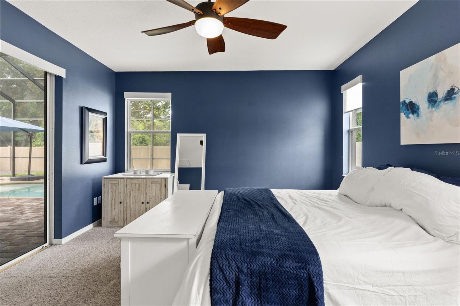 Multiple windows and direct access to the screened lanai bring natural light and the Florida outdoors right into the primary suite. - 1419 BLUE MARLIN BLVD, HOLIDAY