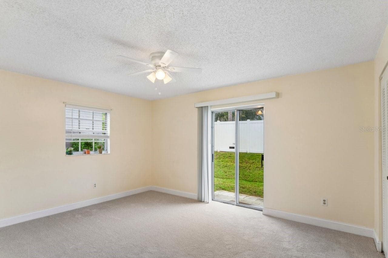 The bedroom has a slider, window, ceiling fan, access to the bathroom and walk in closet, and brand NEW carpeting. - 6709 DEVONSHIRE LN #10A, NEW PORT RICHEY