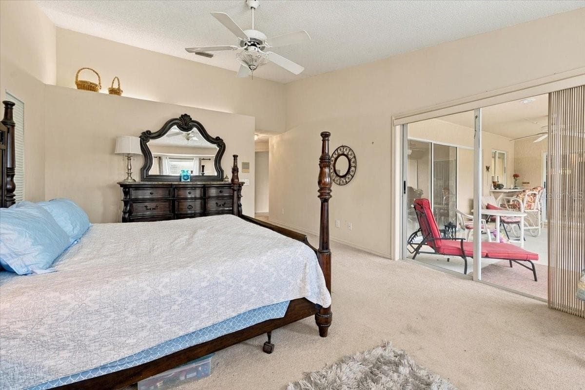 Primary Bedroom with sliding doors out to the back screened lanai - 4437 FLINTLOCK LOOP, LAKELAND